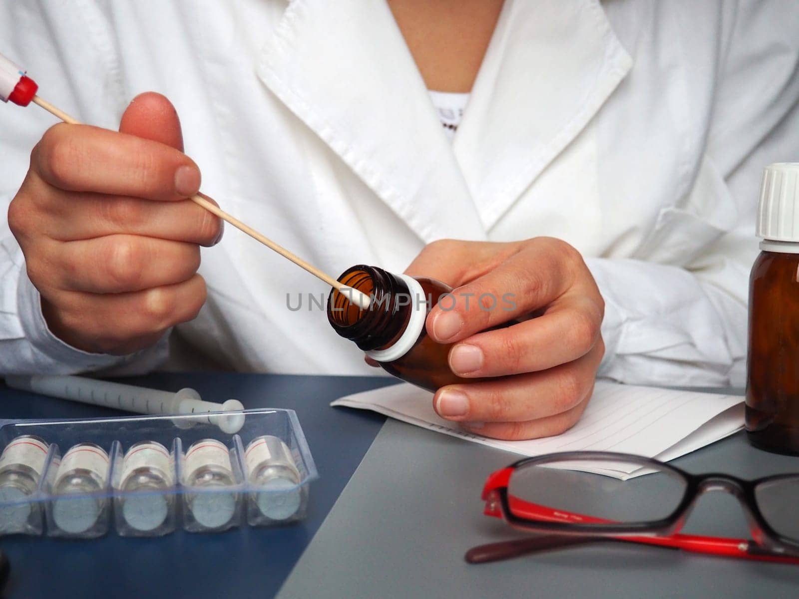 test in the hands of a doctor. Doctor, nurse or laboratory assistant at work in the laboratory. On the table are glasses, measuring instruments, paper, medicines in bottles.