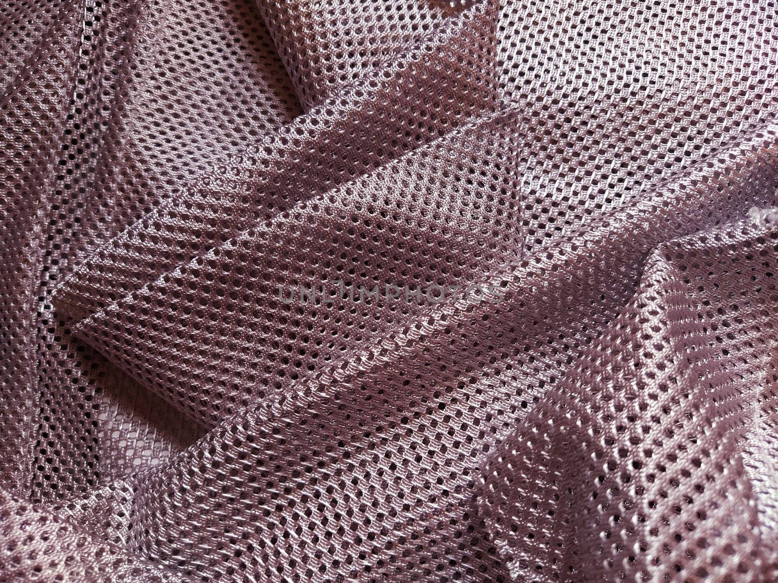 Synthetic polyester fabric with holes. Abstract background. Wave-folded pink fabric. Furniture upholstery.