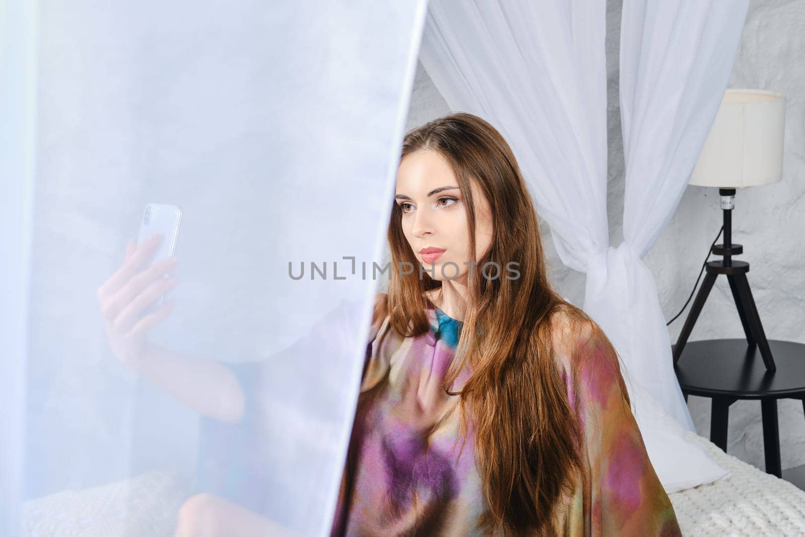 How to spend time at home? Cute woman makes self video for social media in bedroom.