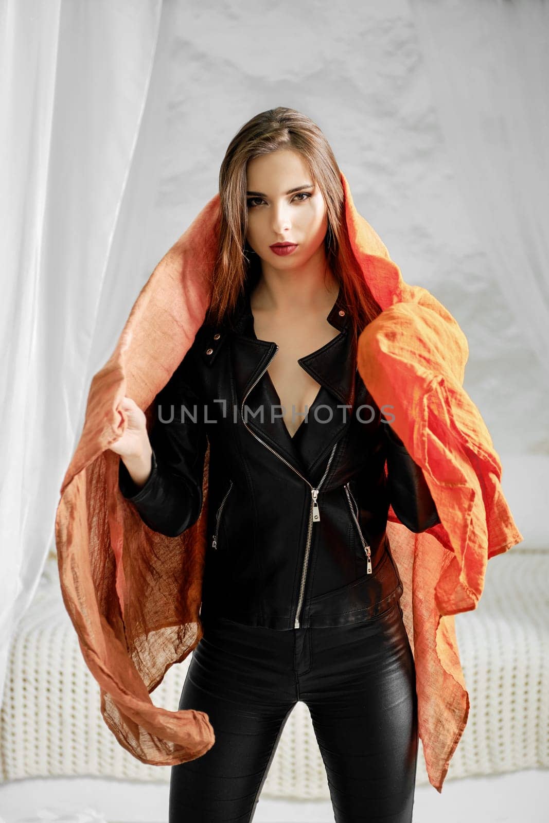 Woman in leather jacket wrapping silk scarf over her neck