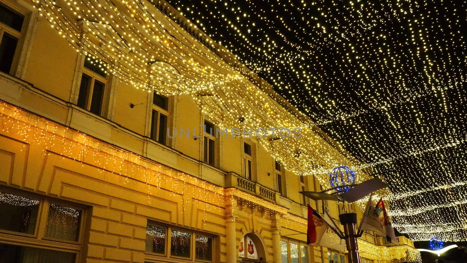Hanging garlands against the background of the night sky. Festive decoration of city streets. Garlands of yellow, white and gold lights and bulbs. Beautiful background for New Year, Christmas holiday