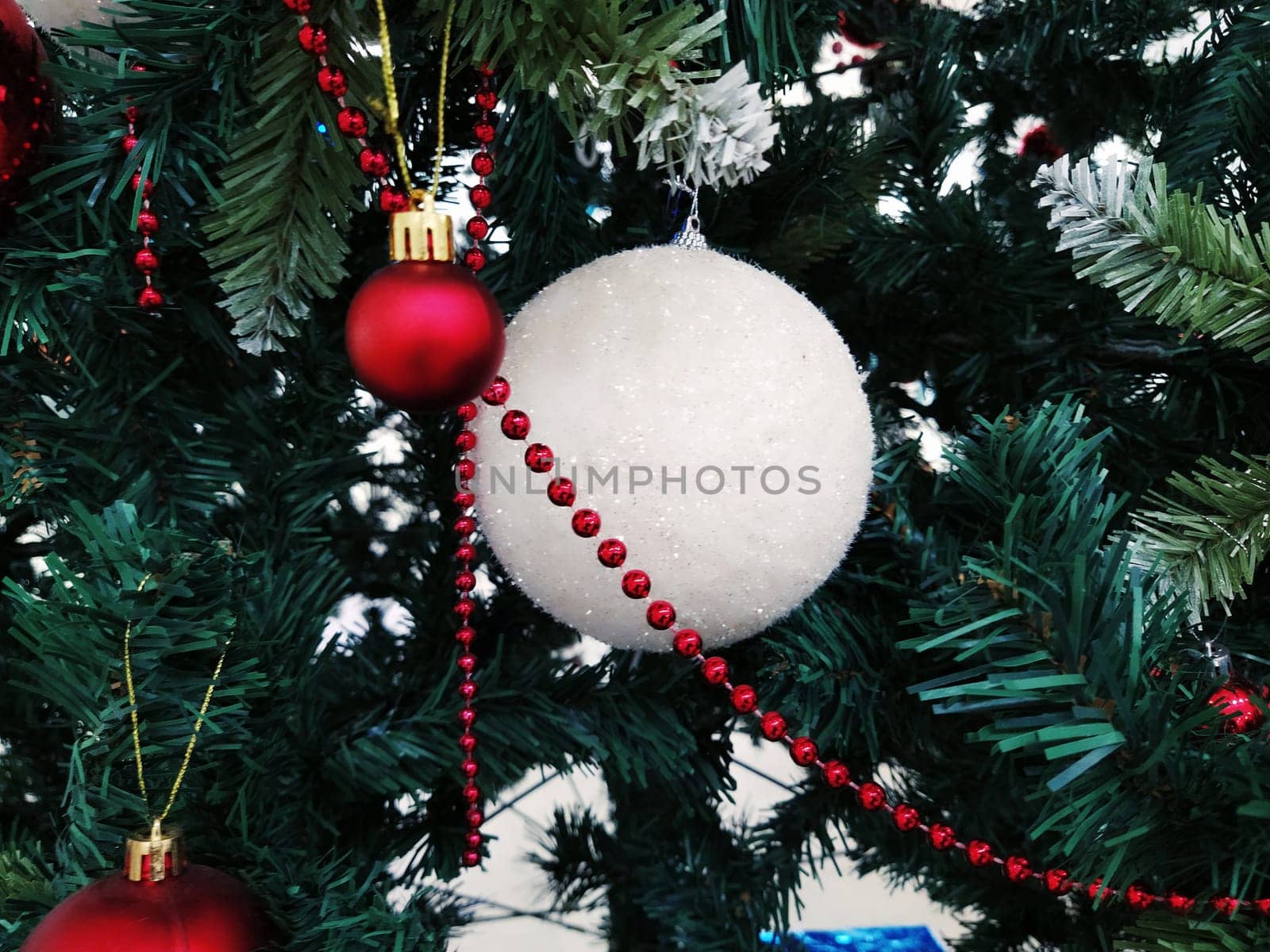 Christmas tree with decorations, Christmas balls and toys. Red and white hanging ornaments. Large and small balls, red beads