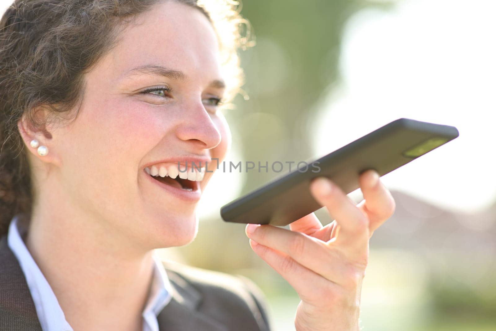 Happy businesswoman dictating message on phone
