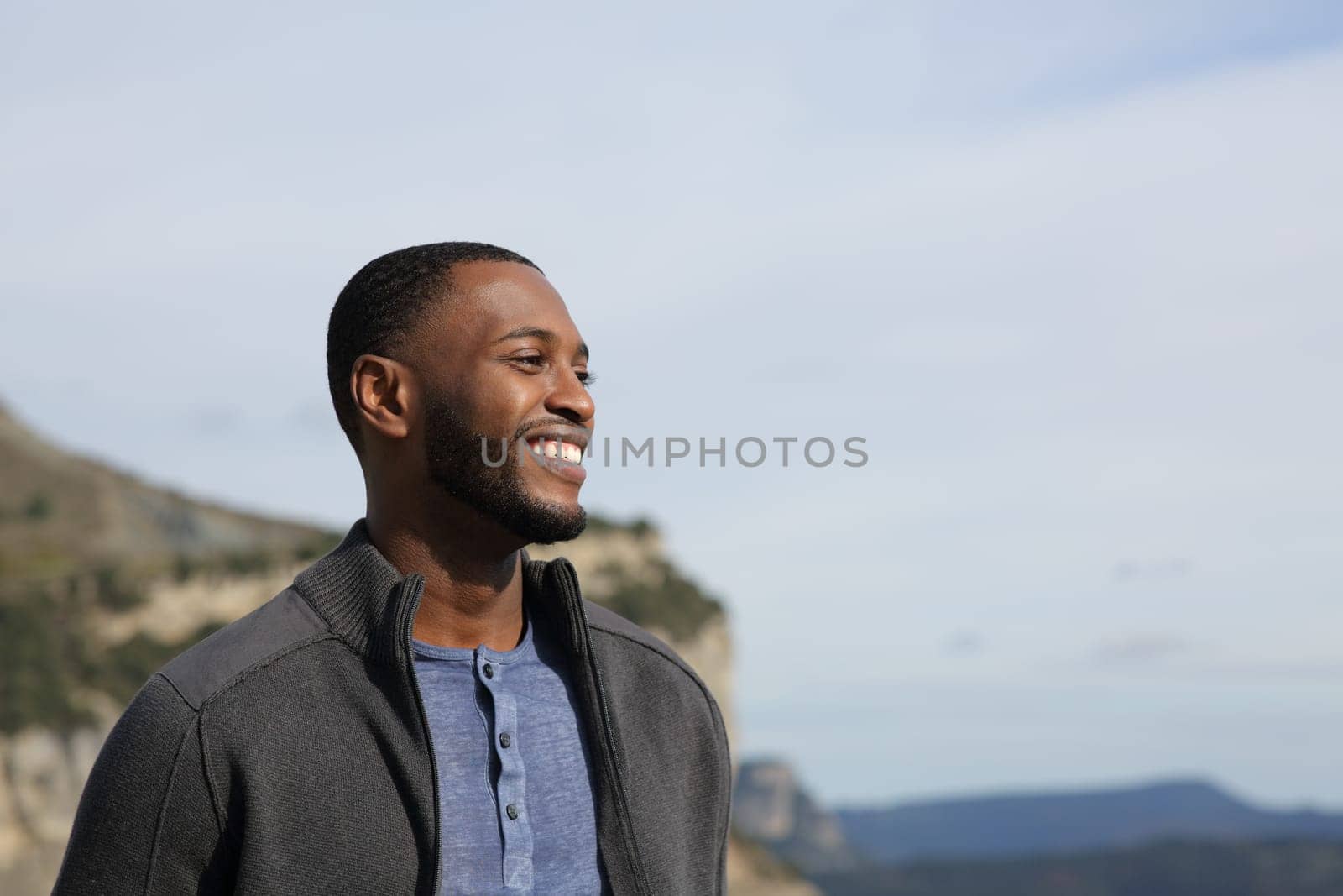 Happy black man contemplating views smiling in nature