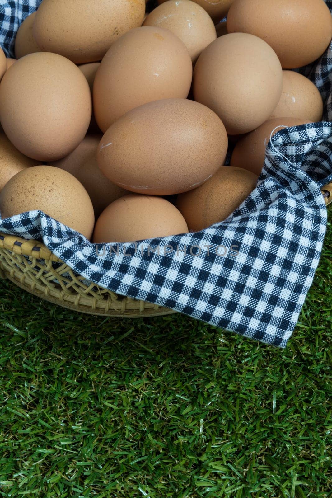 Basket contains group of chicken eggs put on grass.