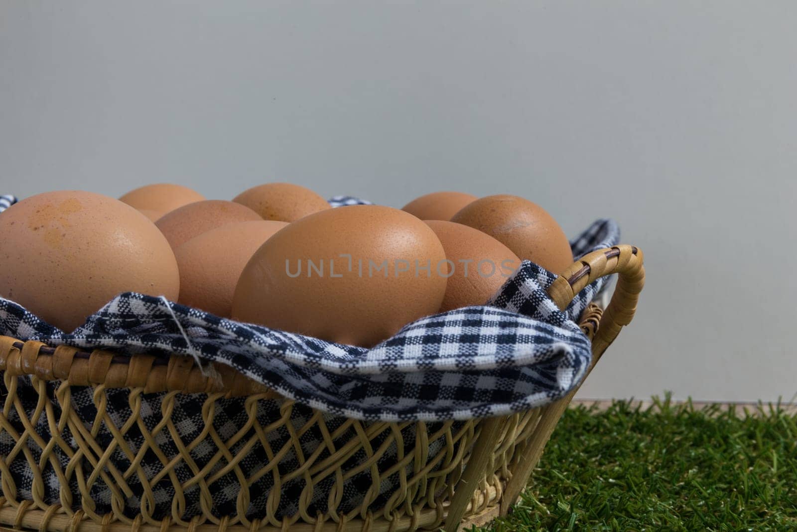 Basket contains group of chicken eggs put on grass.
