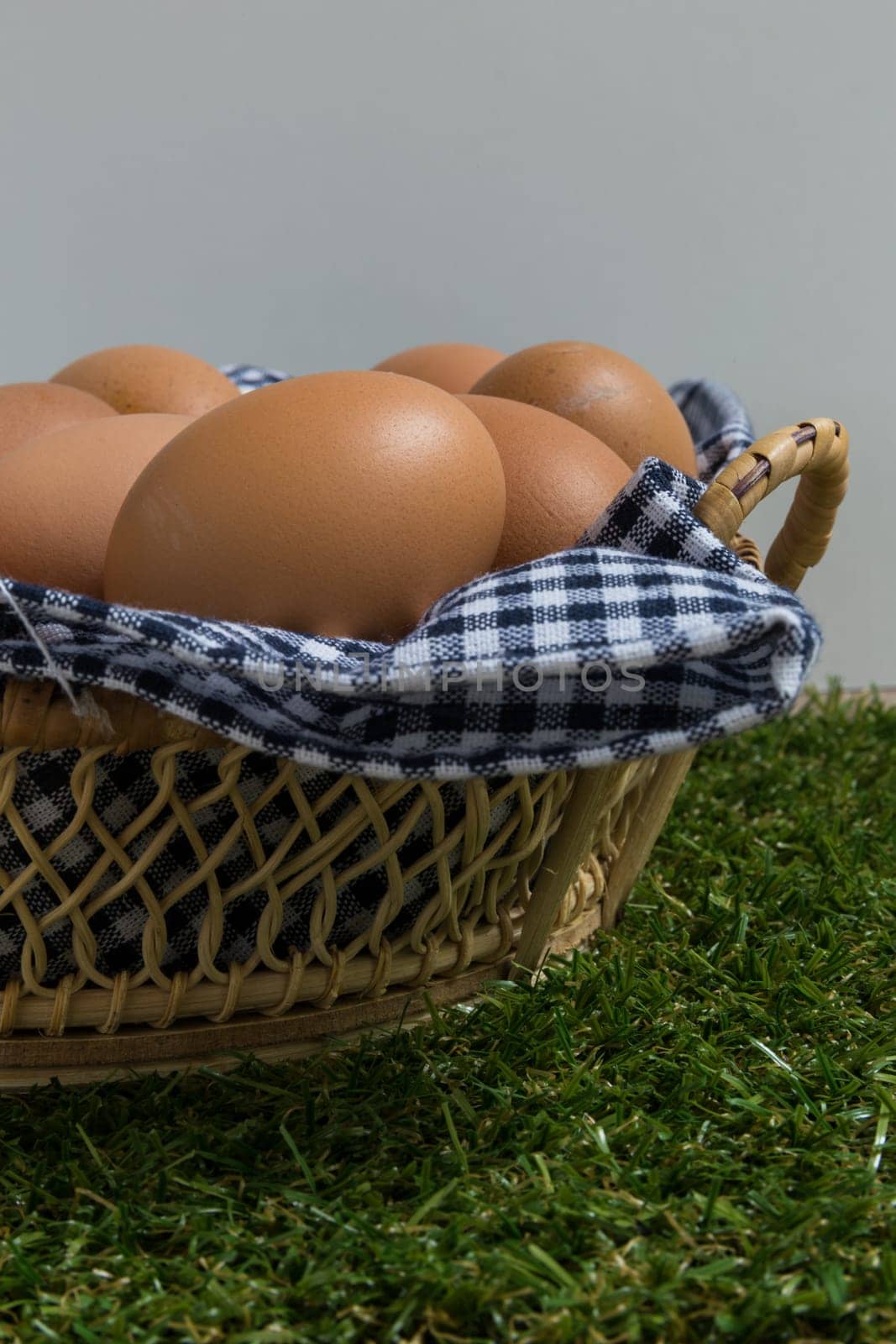 Basket contains group of chicken eggs put on grass.