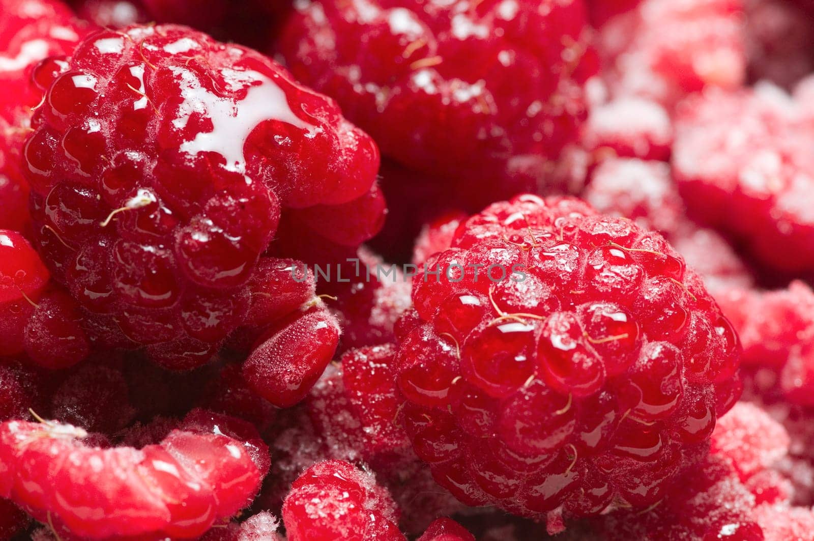 format-filling macro view of thawing raspberries with isolated frost crystals
