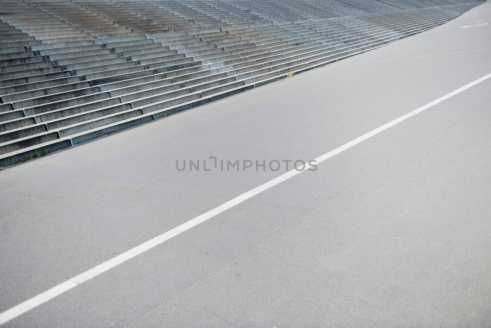 elevated diagonal view of a walkway with white dividing line and adjacent wide concrete staircase
