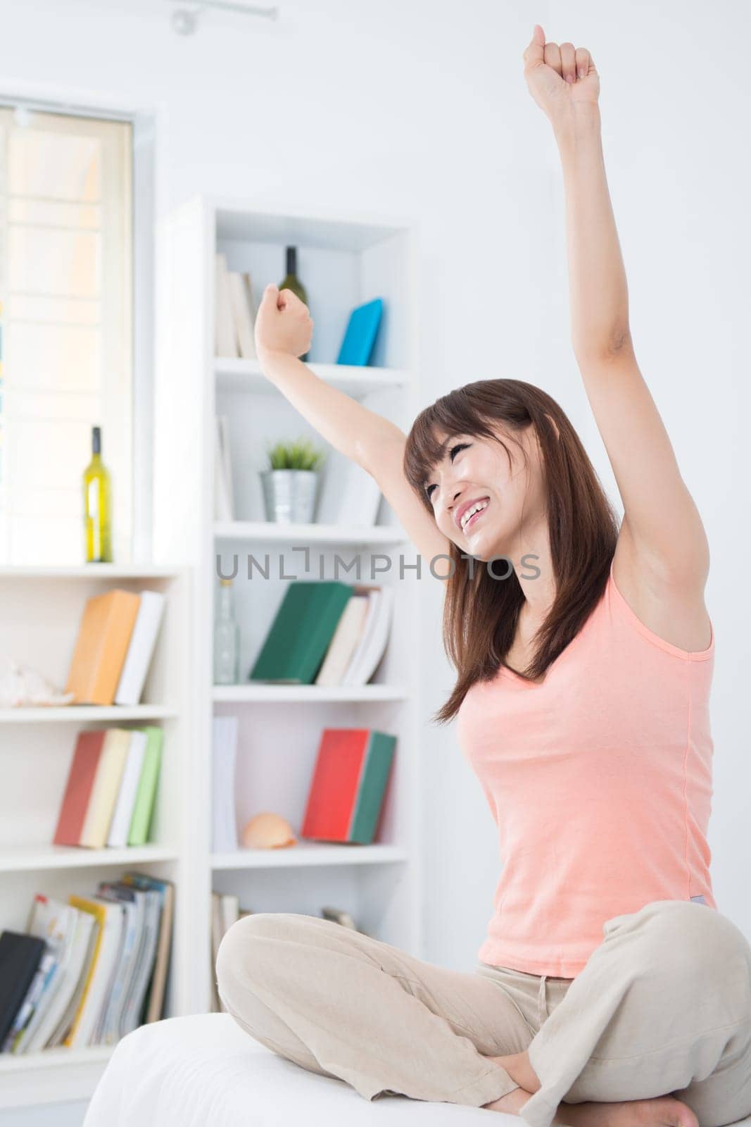 Portrait of Asian girl woke up and stretching arms in the morning. Young woman indoors living lifestyle at home.