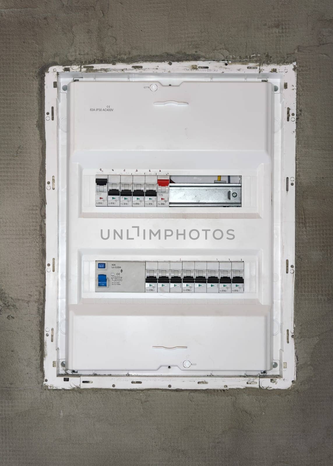 Box with electric switch fuses or circuit breakers installed on bare wall in new house construction site.