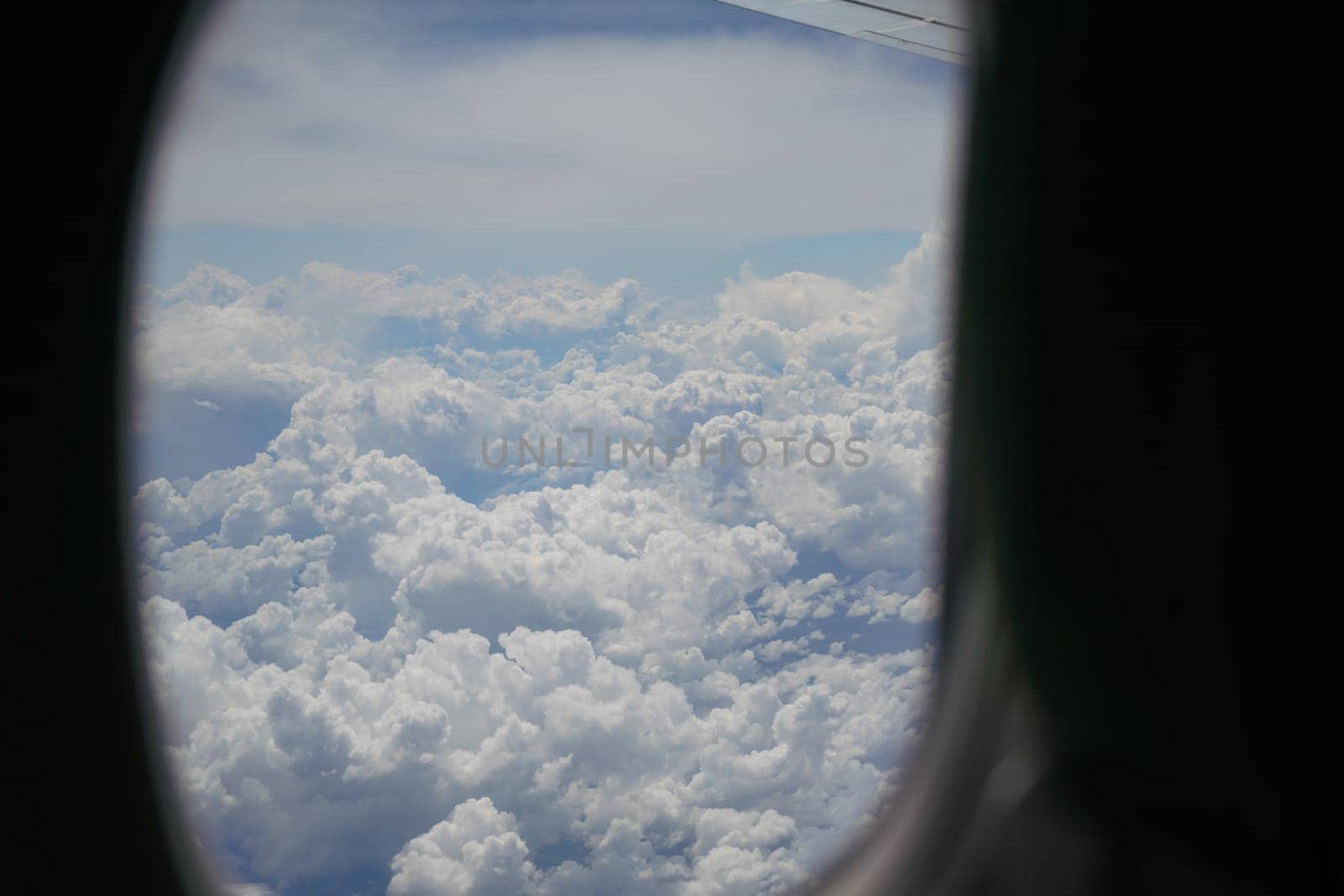 View from commercial airplane window, fluffy clouds visible in background.