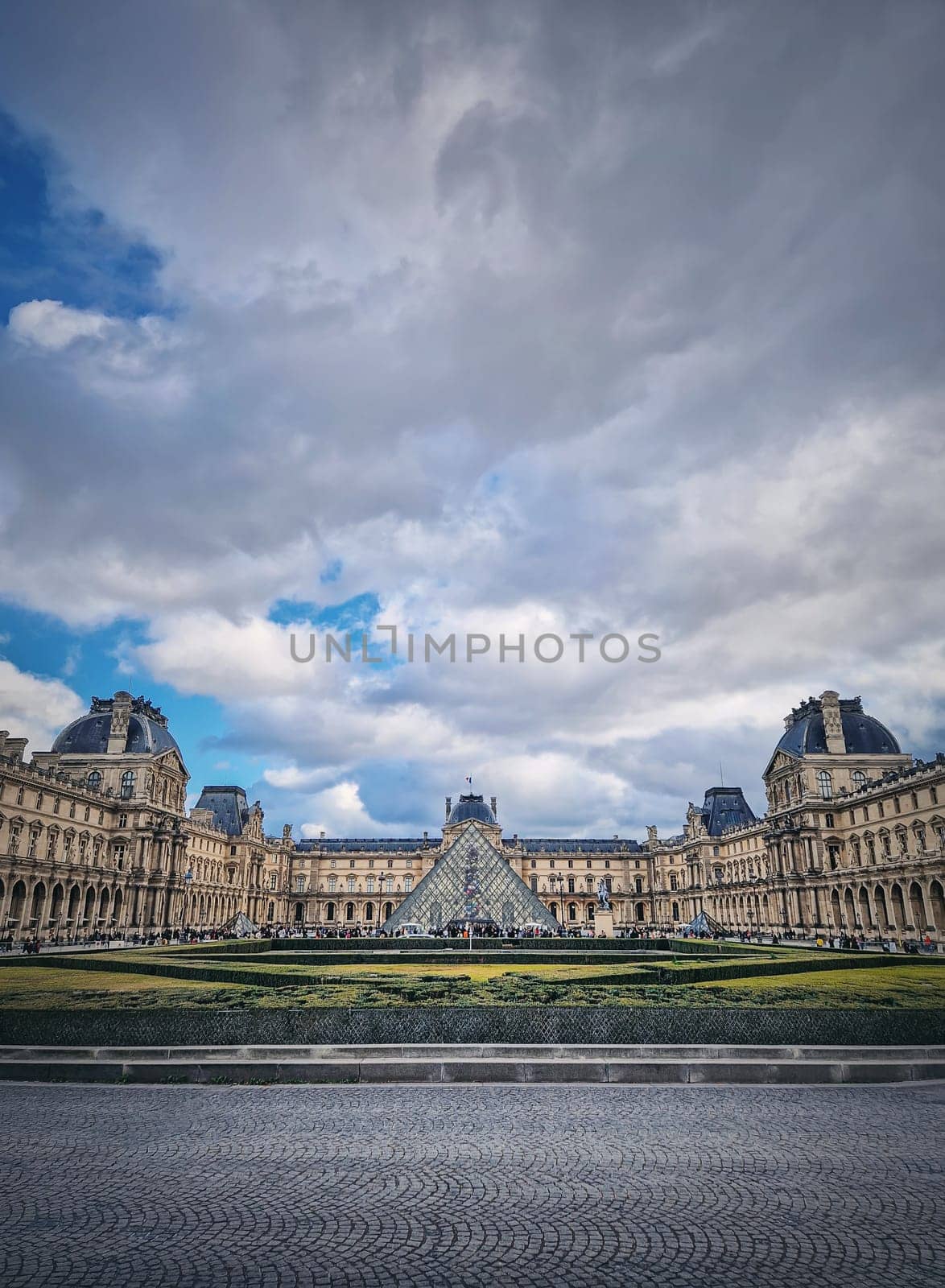 Outdoors view to the Louvre Museum in Paris, France. The historical palace building with the modern glass pyramid in center, vertical background.
