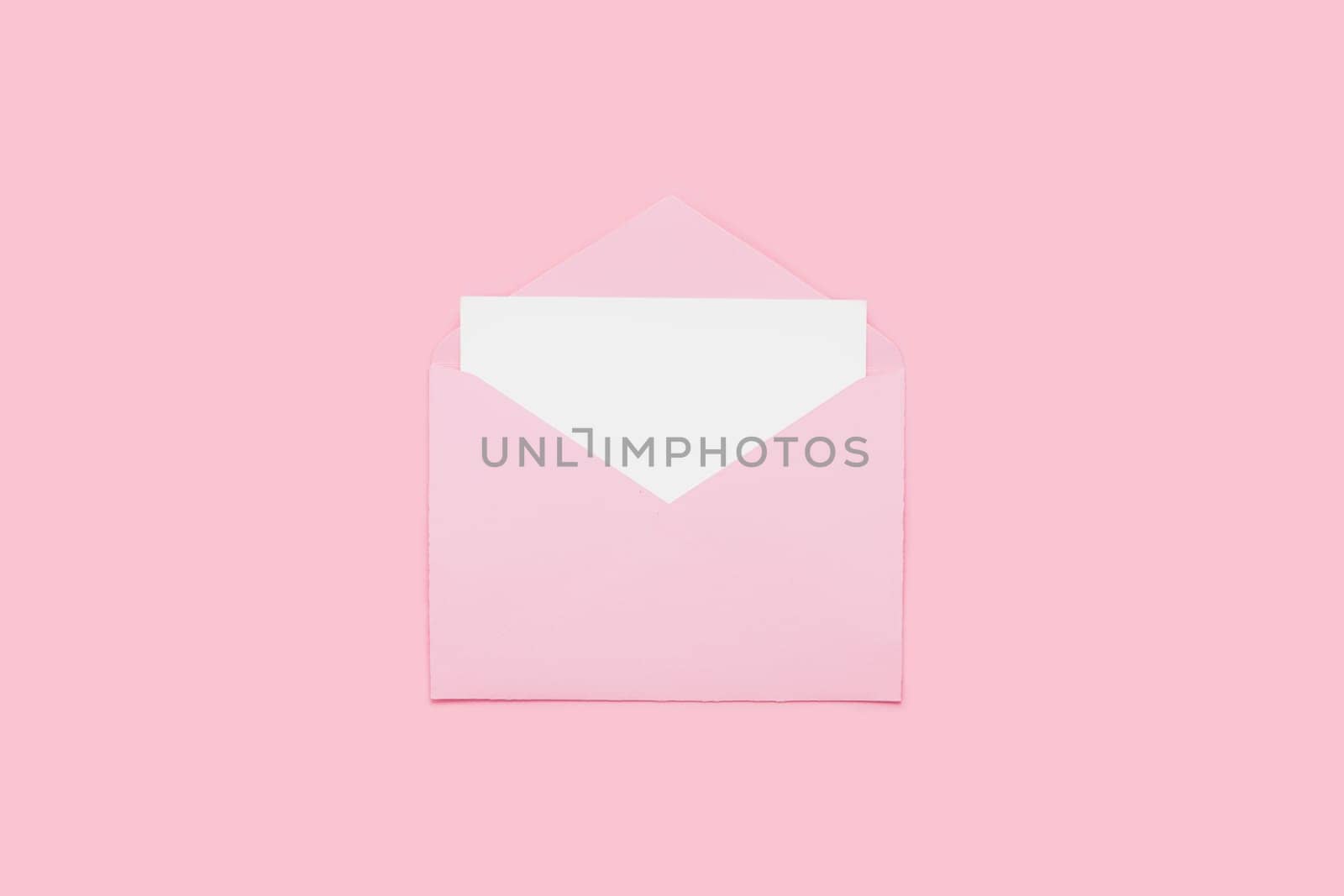 Closeup on blank empty white paper card in pink opened envelope isolated on pink pastel color background. Love letter minimal concept. Conceptual layout template with text place on postcard. Mock-up