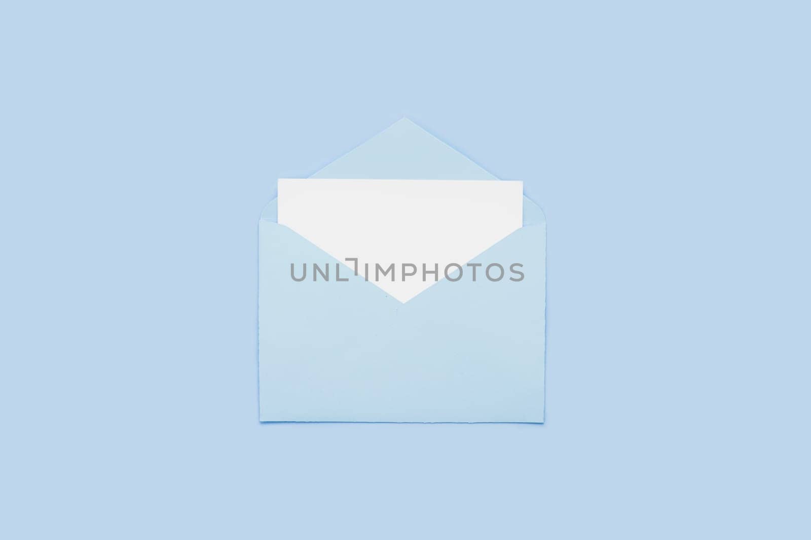 Closeup on blank empty white paper card in blue opened envelope isolated on blue pastel color background. Love letter minimal concept. Conceptual layout template with text place on postcard. Mock-up