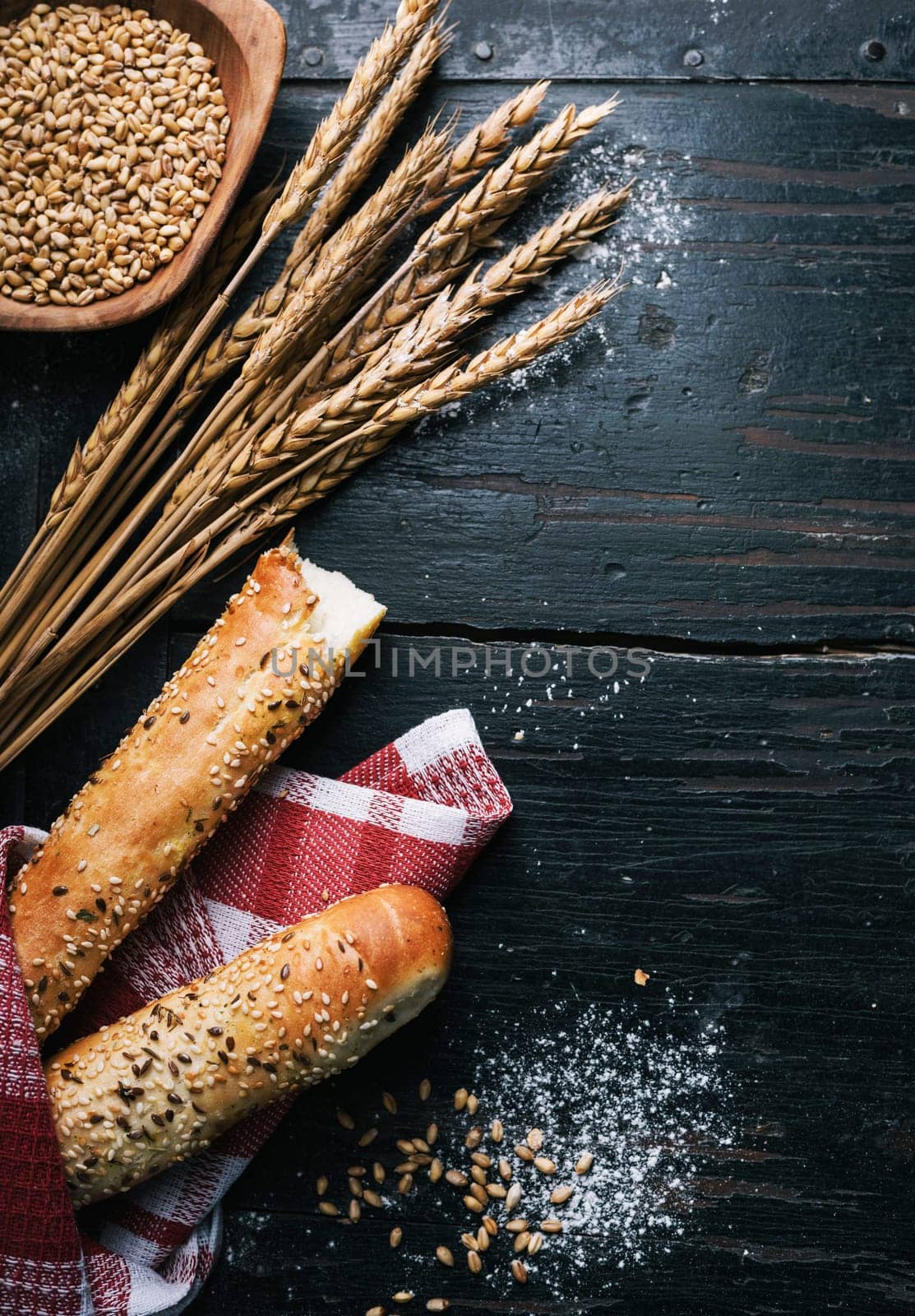 Fresh french baguette bread, organic flour and wholegrain wheat on dark vintage wooden board form above. Top view of traditional baked bread. Bakery shop menu background.