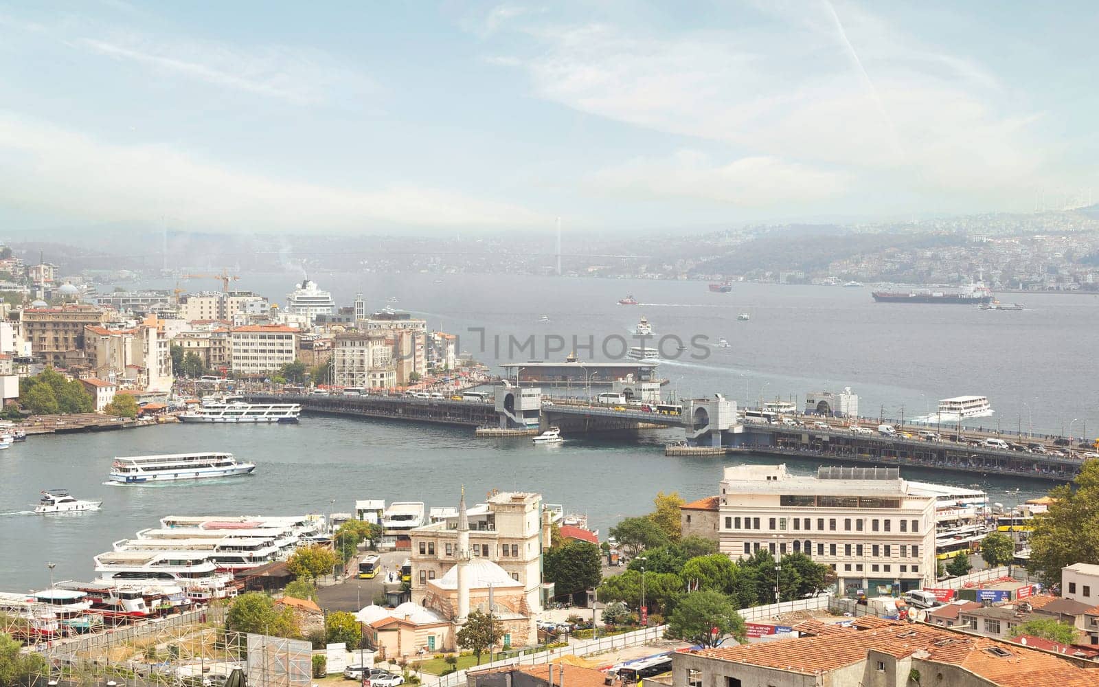 Aerial view of Golden Horn, with Galata Bridge and Karakoy Ferry Terminal with ferry boat approaching the terminal, and Bosphorus bridge in the far end, Istanbul, Turkey