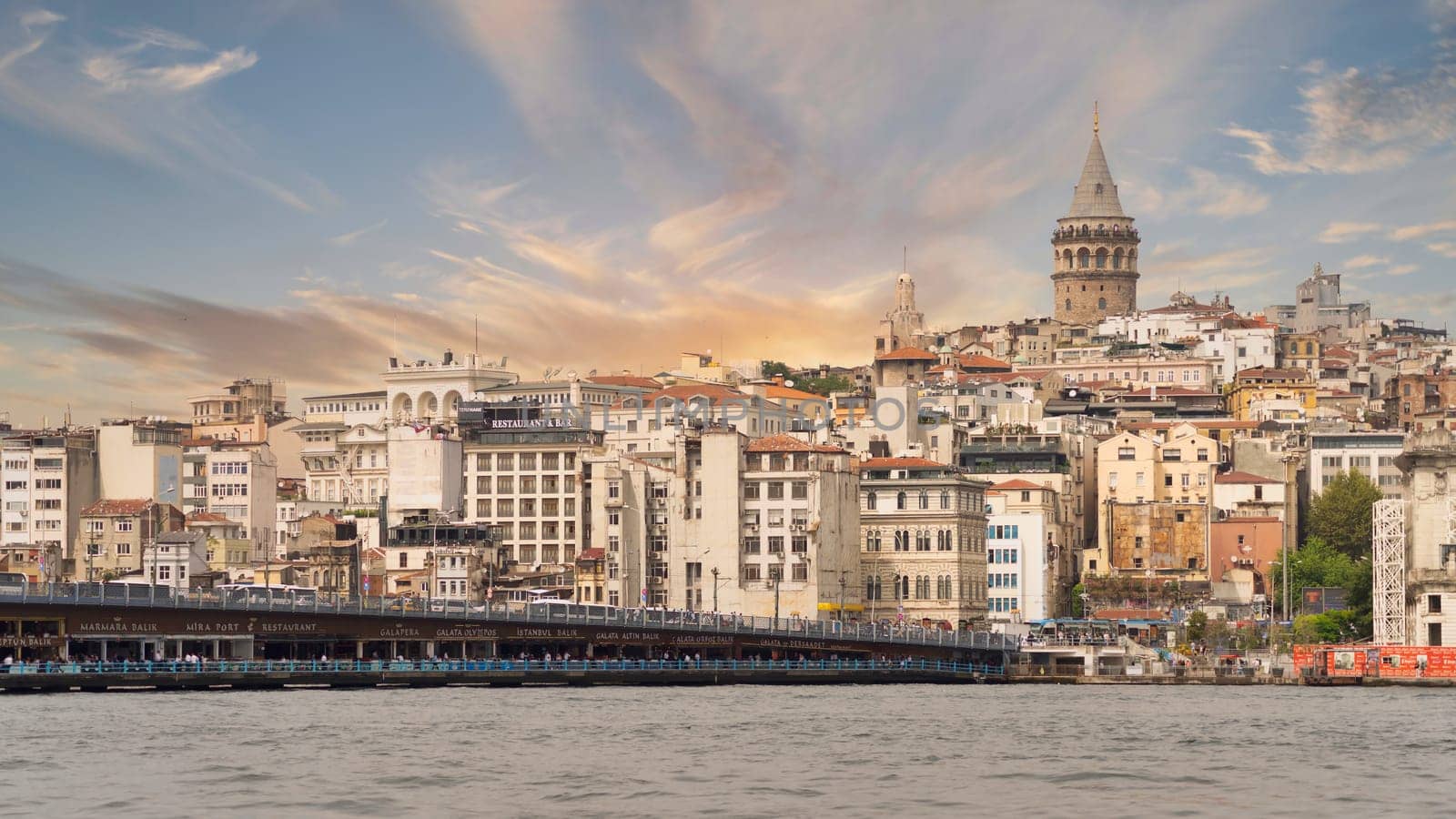 Istanbul, Turkey - August 25, 2022: City skyline including Galata Bridge with traditional fish restaurants in the passage under the bridge, and Galata Tower in the far end