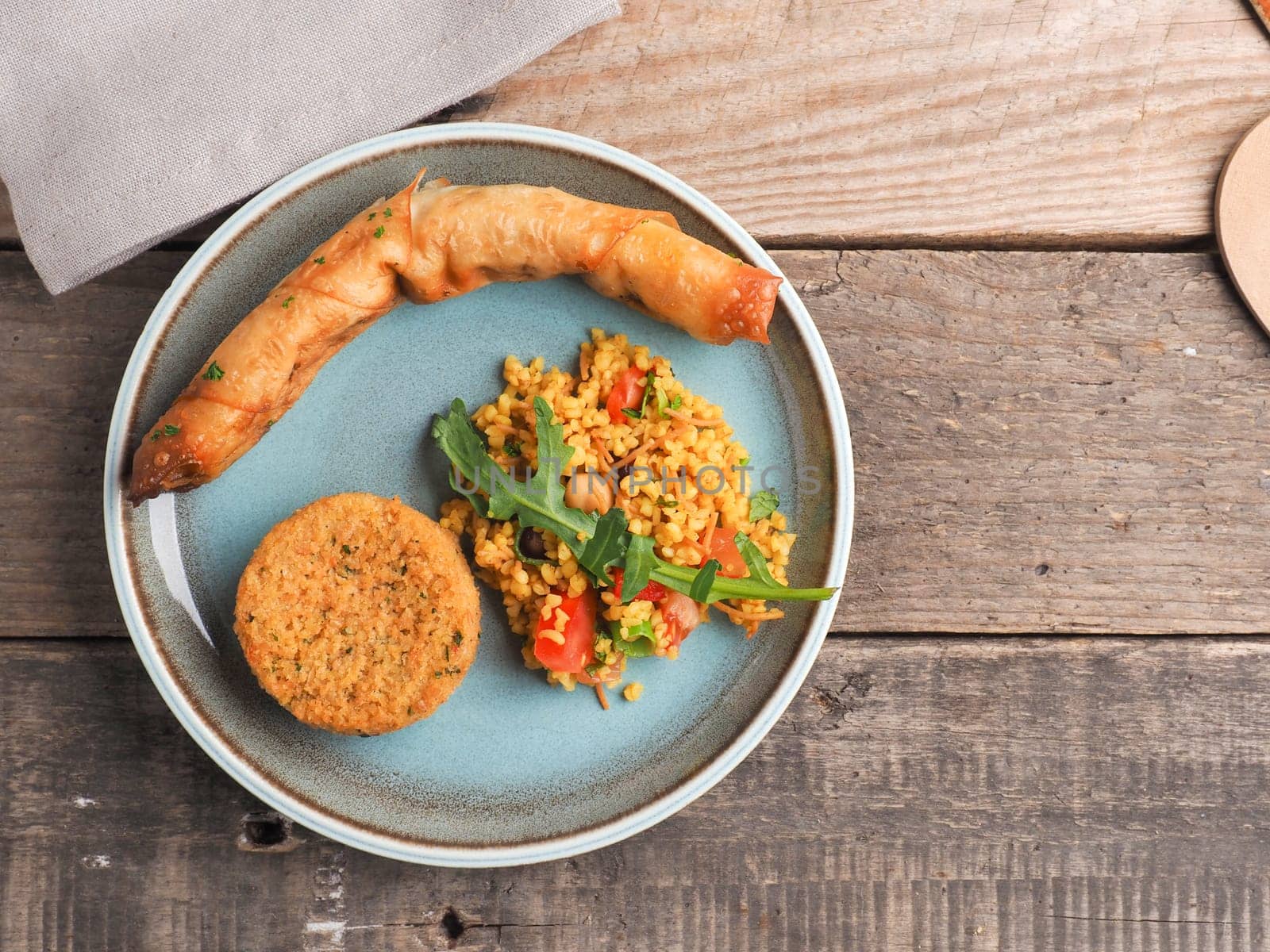 Tasty Falafel with spicy bulgur and a vegetarian dough roll on a ceramic plate, traditional heatlhy food, view from above