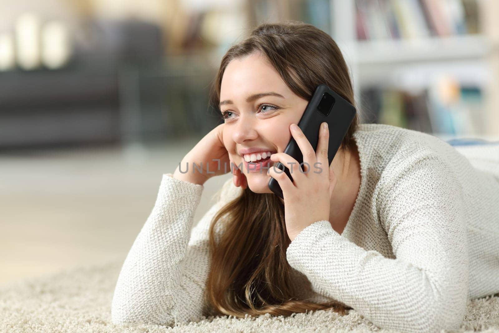 Happy teen talking on phone on the floor at home