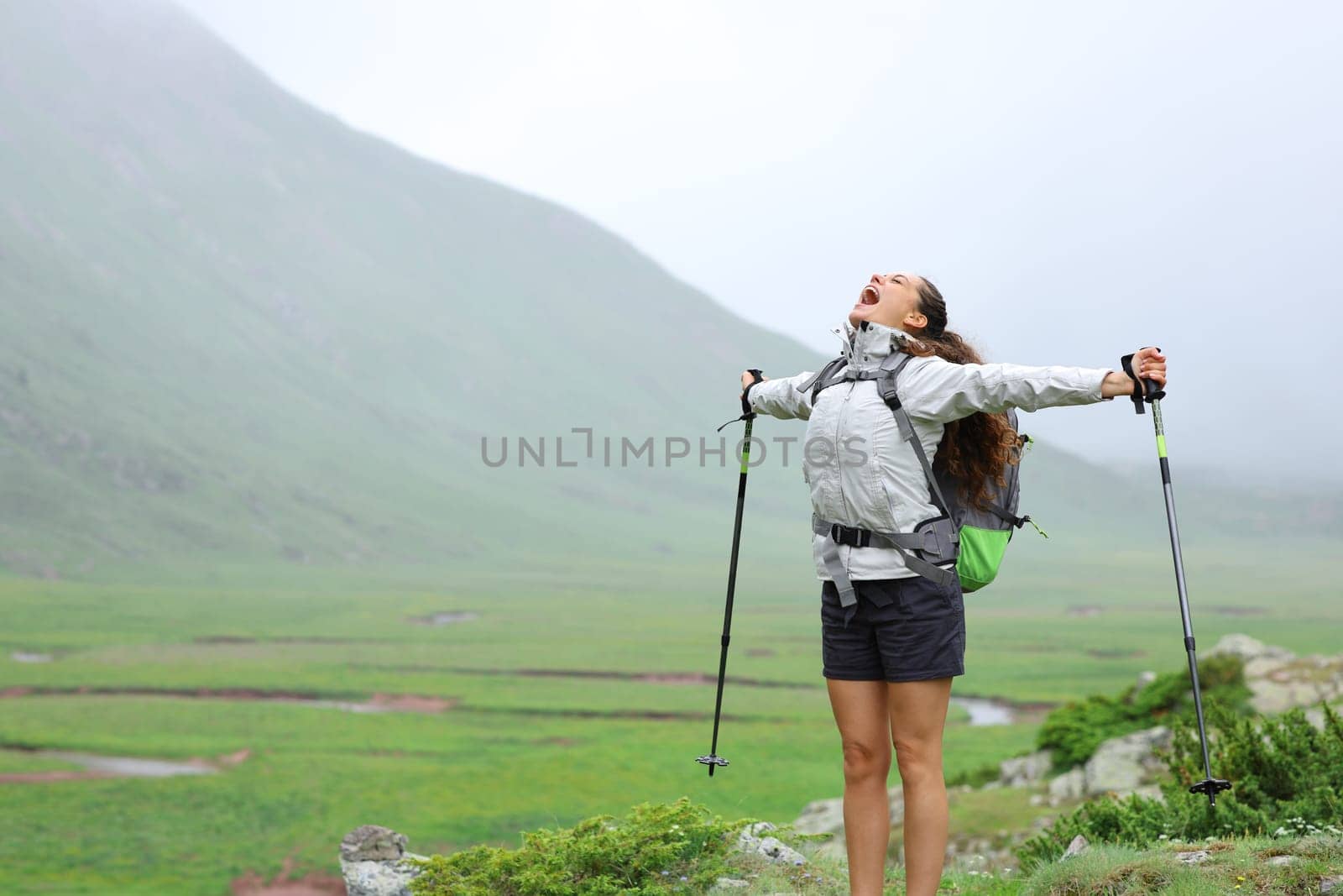 Excited hiker celebrating her healthy life in nature screaming to the air