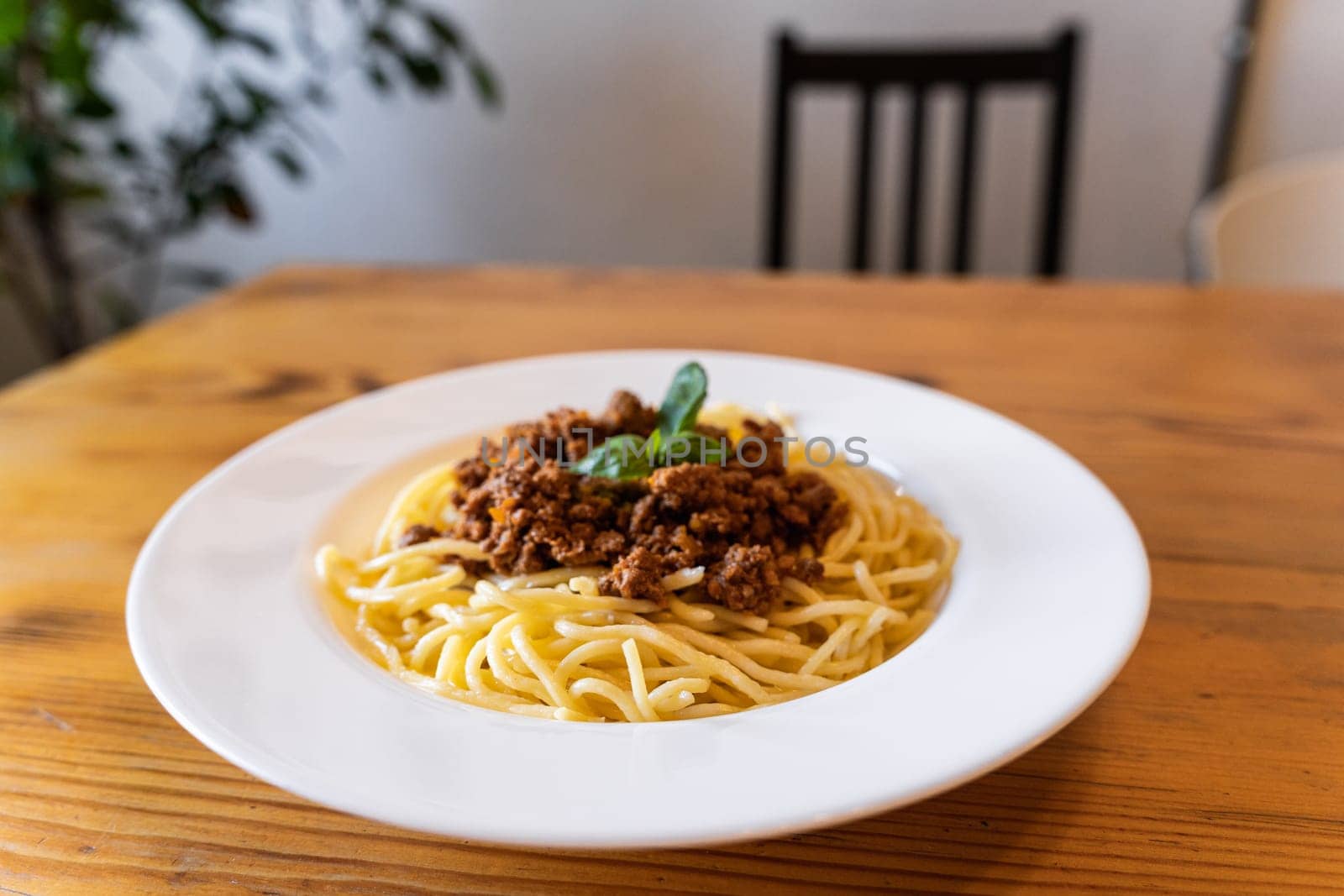 Plate with traditional Italian pasta spaghetti bolognese on a wooden table in the restaurant