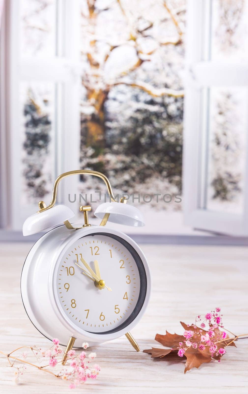 Vintage alarm clock on table with open window, winter time