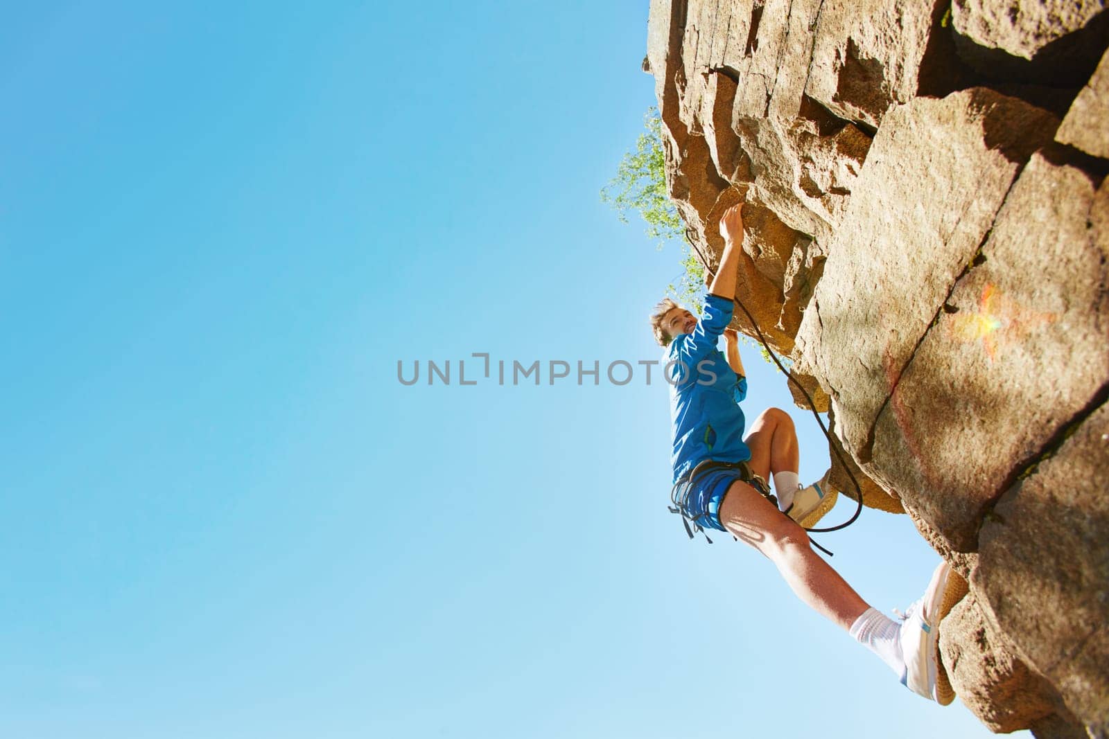 Young man in activewear climbing the rock