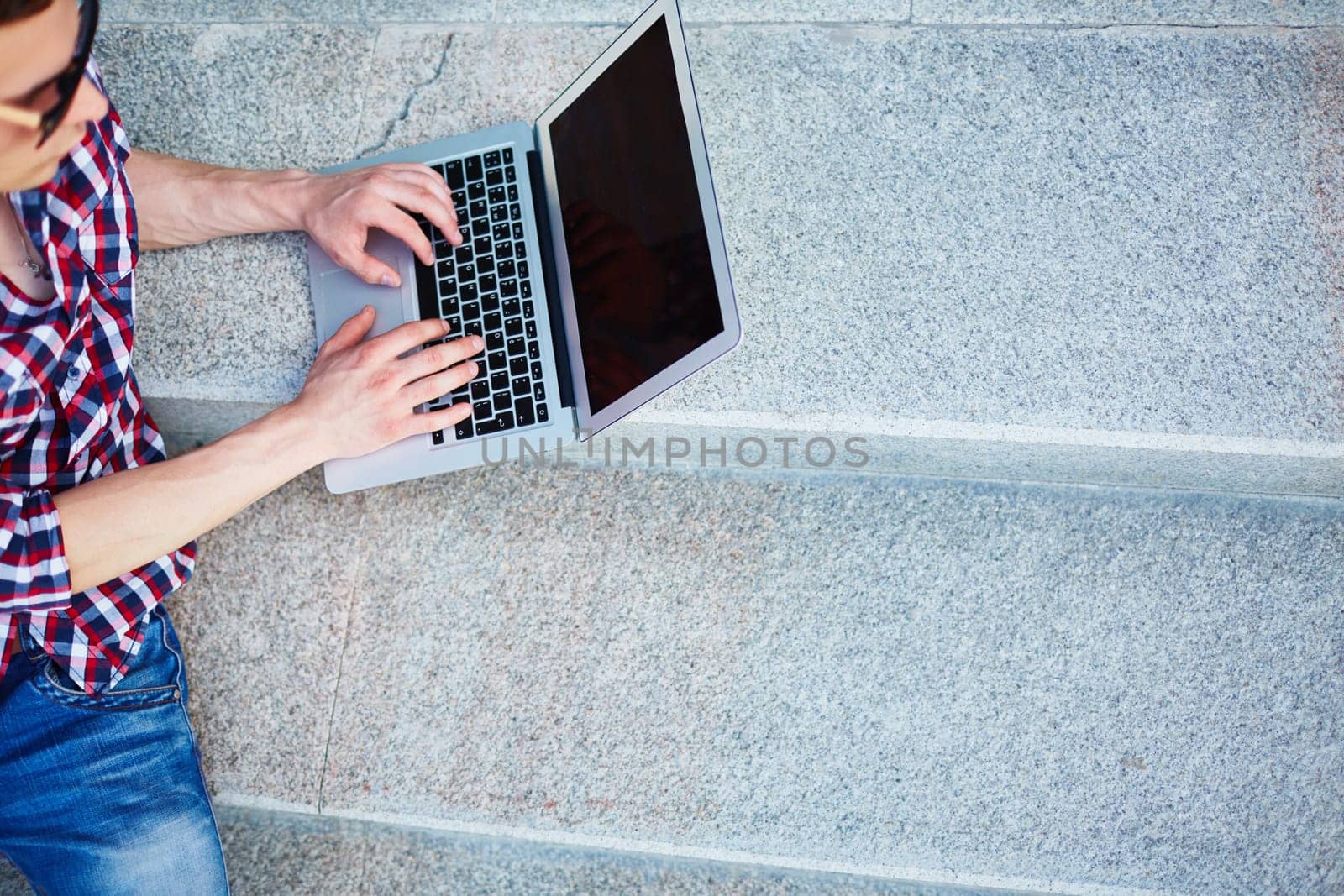 Modern guy typing on stairs outside