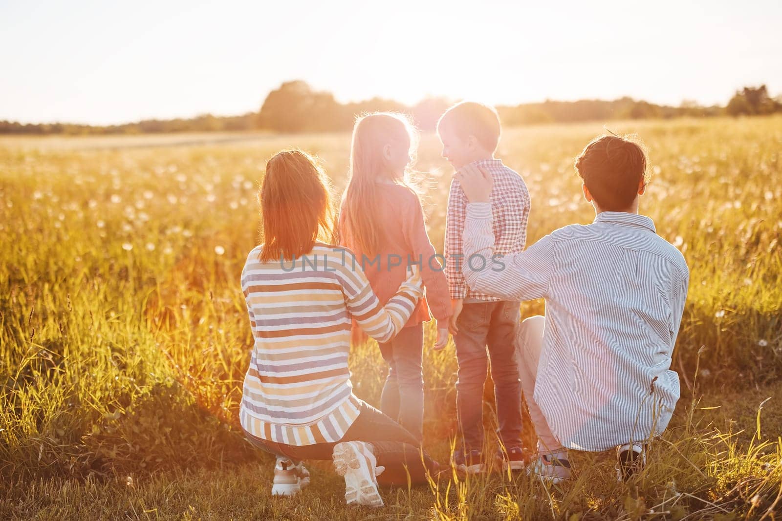 Family standing on the sunset on the field in natural park. Concept of the relationship between people and vacation together.