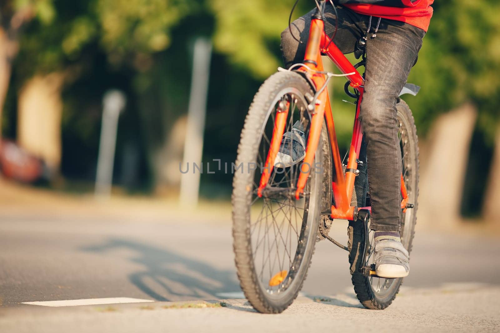Boy riding a bike on the sidewalk along asphalt road. Concept of learning to drive a bicycle and independence.
