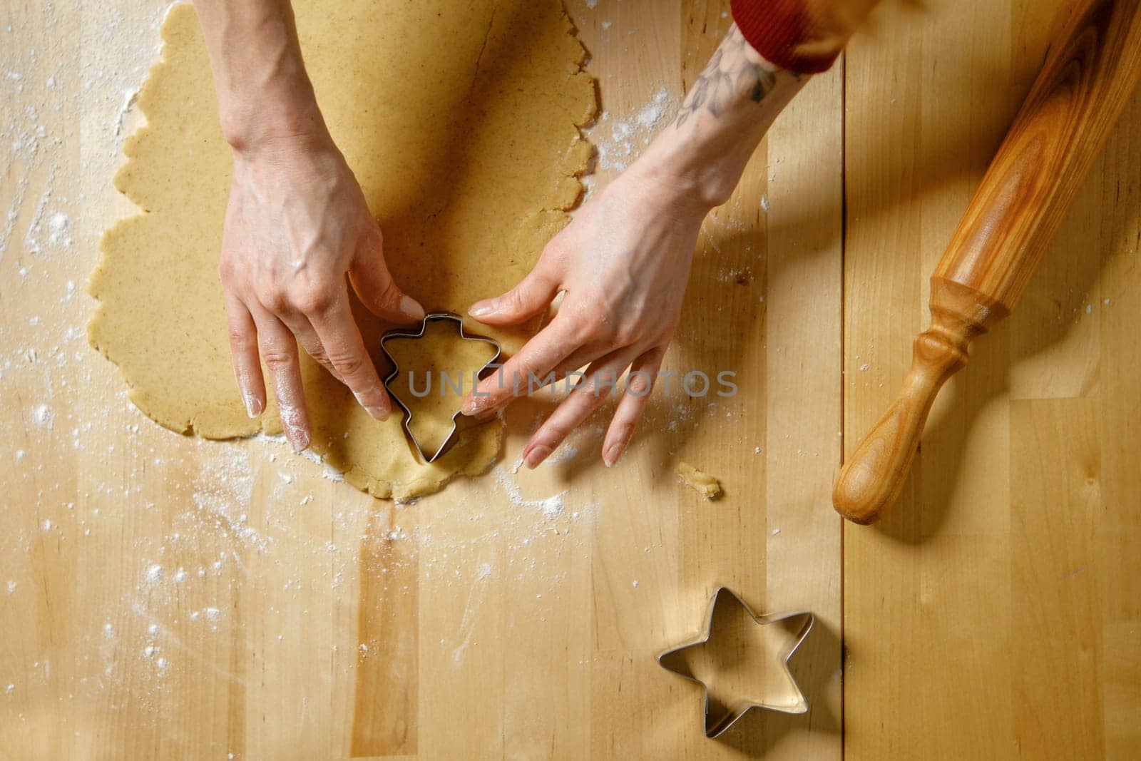 Unrecognizable woman cuts out biscuits from dough with cookie cutter