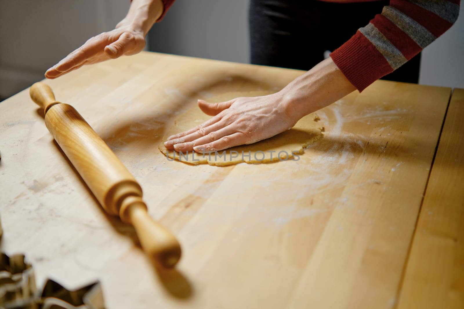 Unrecognizable woman rolls out dough to make ginger cookies