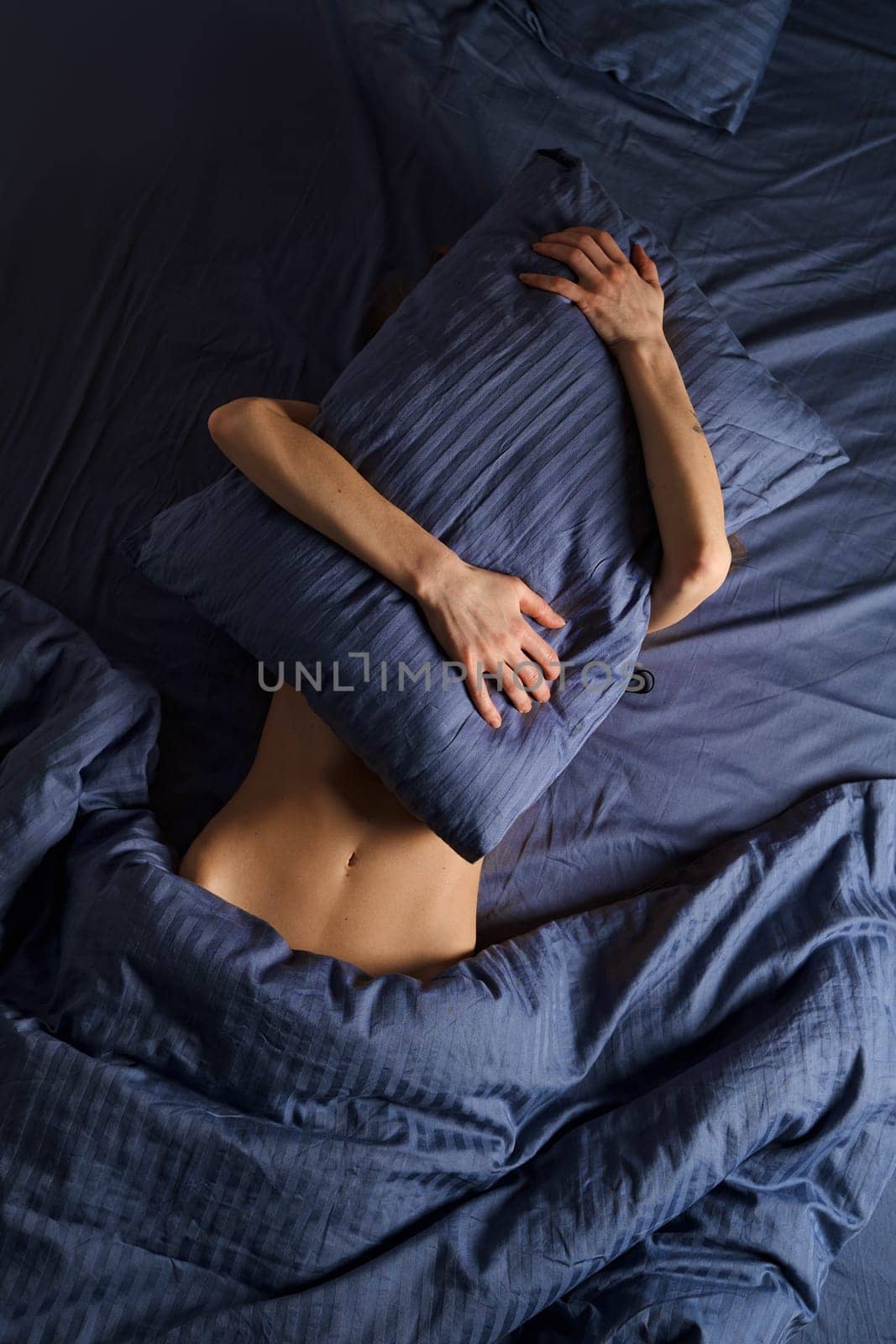 Unrecognizable woman suffer from painful periods, stays in bed and is waiting for the medicine to take effect