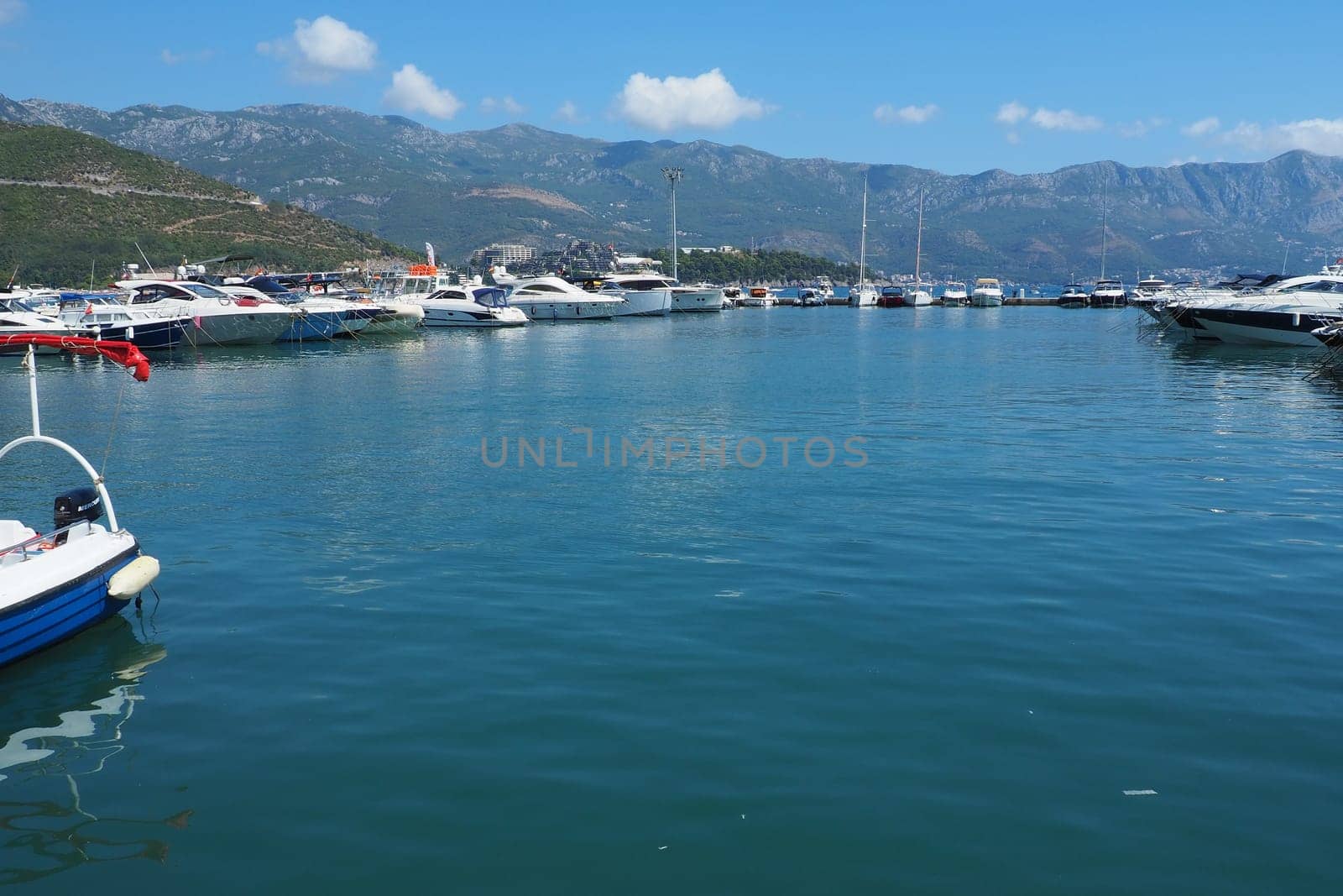 Budva, Montenegro, August 15 2022 Adriatic sea, coast, mountains, sea ripples. Boats and ships are moored to the embankment. Water transport parking. Summer resort trips with tourist water activities.