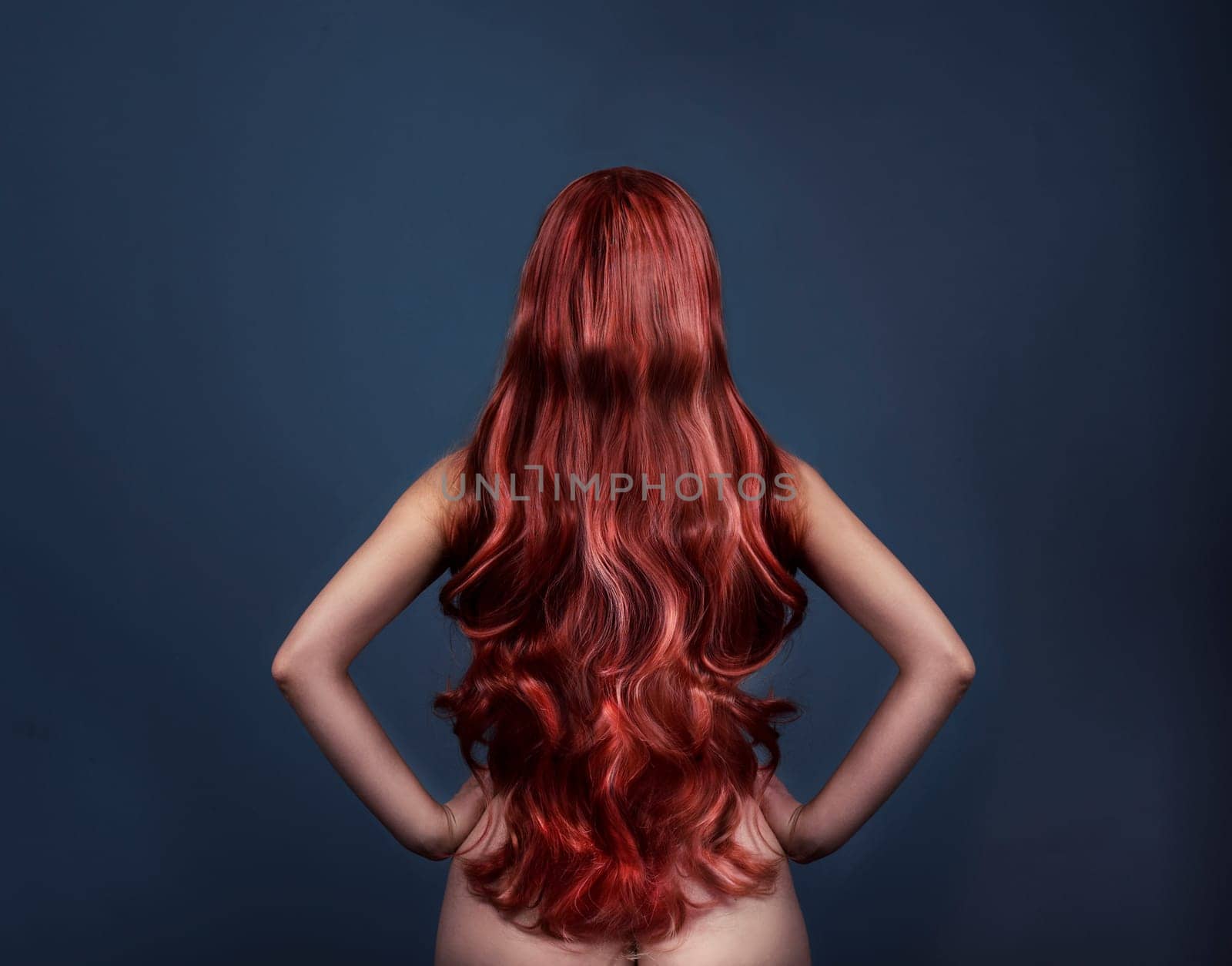 Woman with perfect curly dyed hairstyle from behind. Fashion portrait of red head woman from the back over dark background. Perfect long red hair.