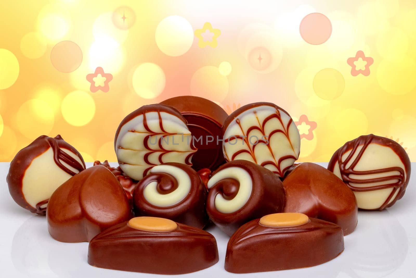 Invitation children's party or birthday party. Beautiful assortment of different chocolate candies sweets on bright table over abstract yellow background with copy space.