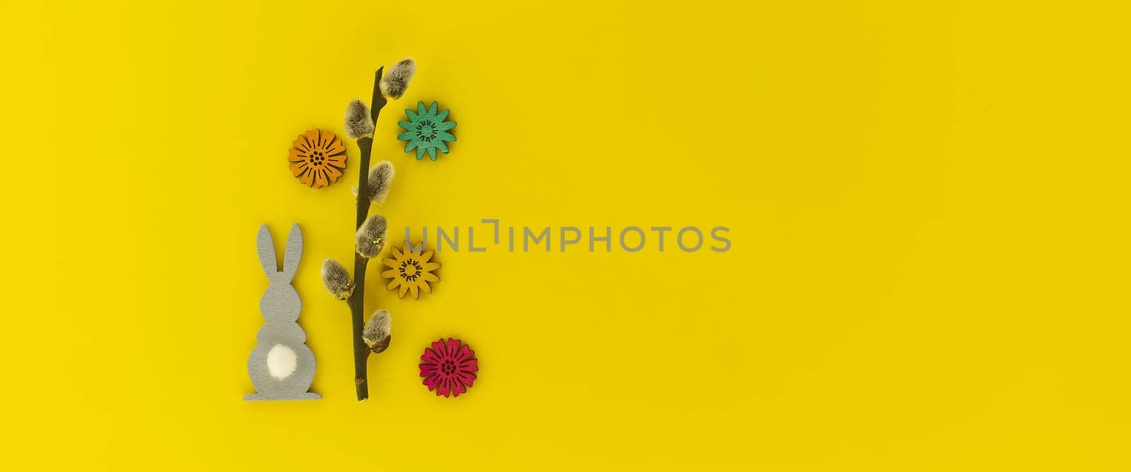 Minimalistic Easter holiday or spring background with Easter Bunny figure, pussy willow branch over a yellow background. Copy space for your text