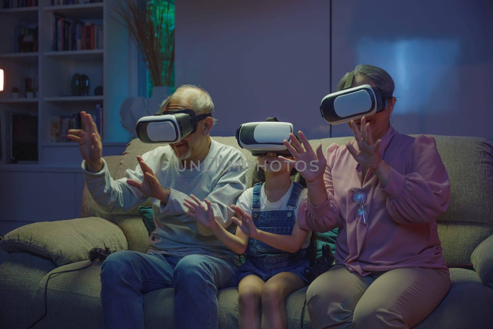 Asian granddaughter and grandparents playing together exciting interesting video games using virtual reality headsets living room at home, elderly with child play VR video game, family entertainment