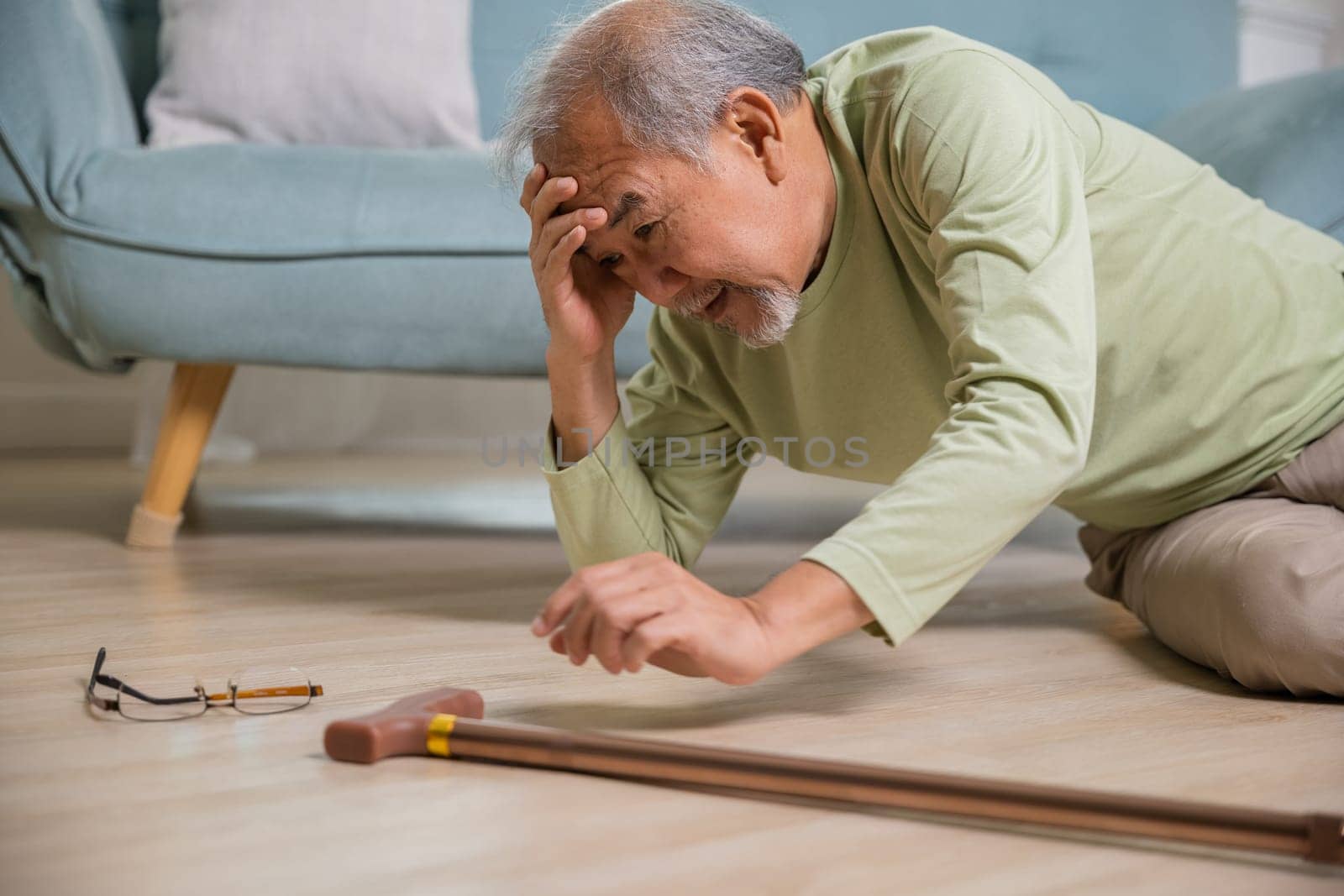 Sick senior old man falling down lying on the ground because stumbled at home alone with wooden walking stick in living room, elderly man grandfather having accident while walk with cane walker