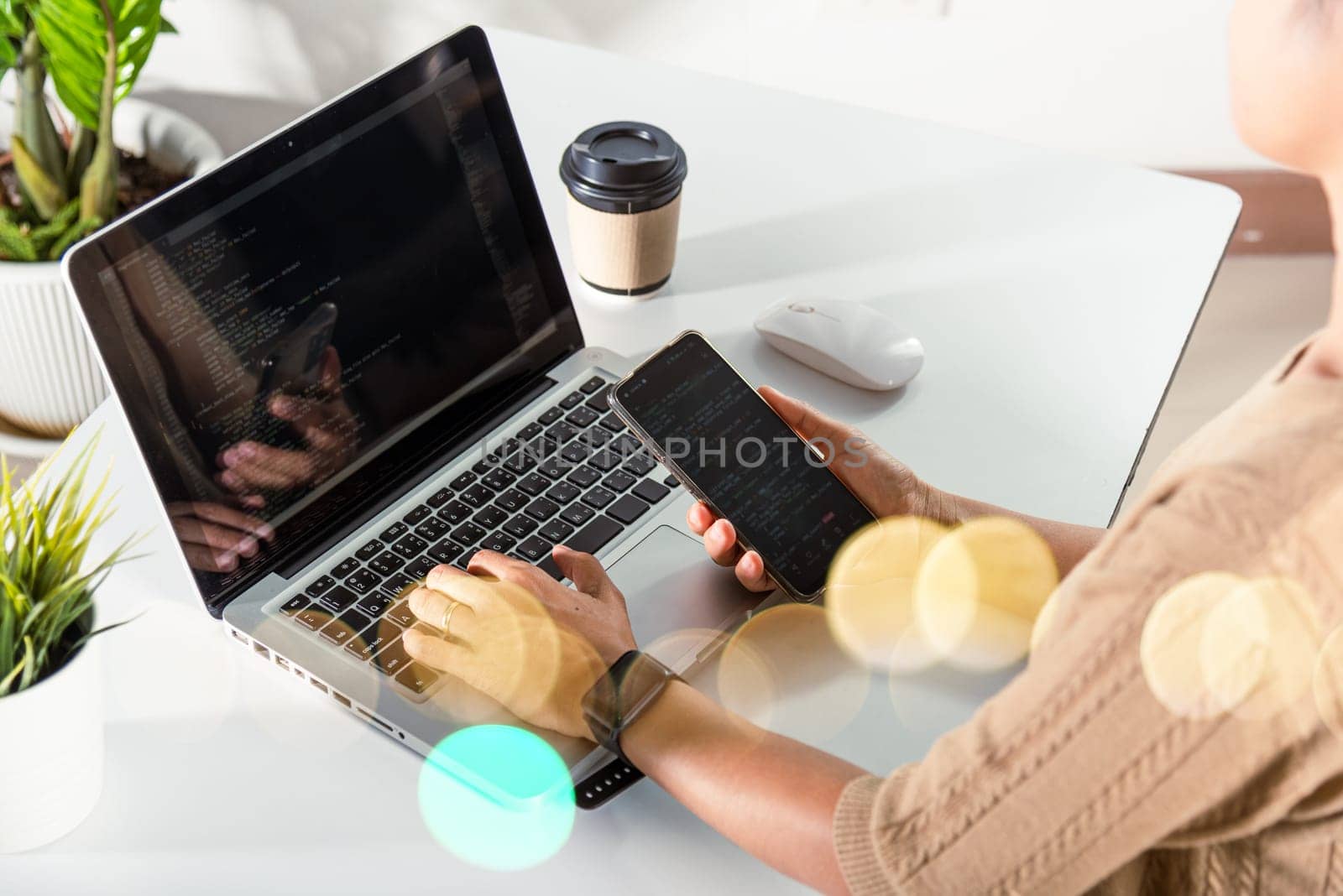 Software developer hands typing data coding programming javascript with laptop computer and mobile phone, Programmer woman looking smartphone program code at workplace, IT startup concept