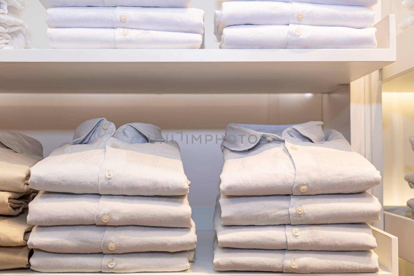 Shelves with colorful shirts neatly folded in clothes store.