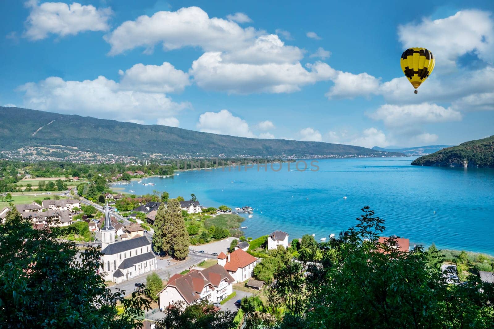 a yellow hot air balloon flying over Annecy lake in the morning, France