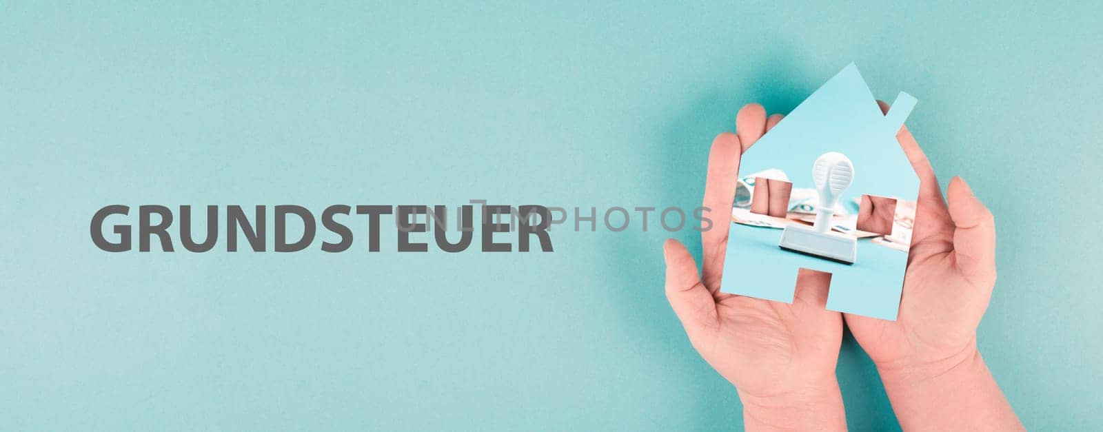 Holding a house in the hand with Euro banknotes and a stamp, new law for property tax, german language