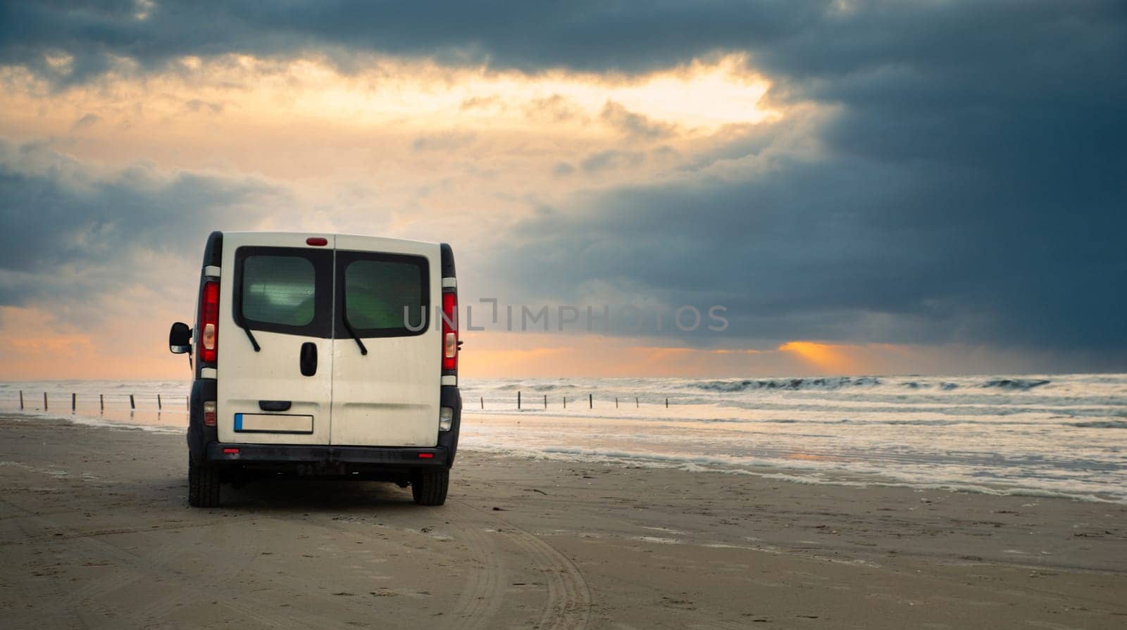 Camper van driving next to the wadden sea at low tide, traveling at the beach of Romo in Denmark, adventure vacation und lifestyle