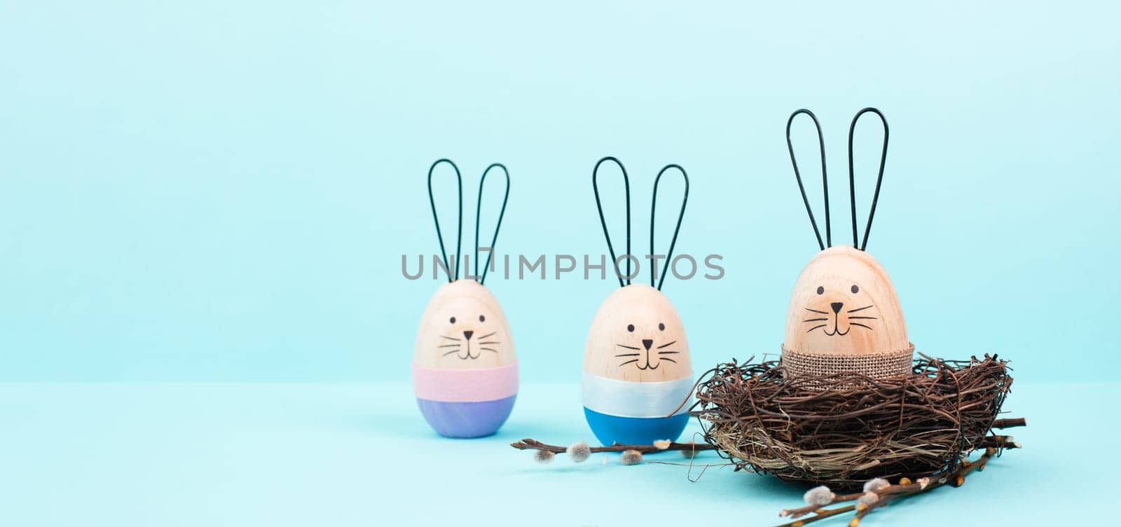Easter bunny or rabbit group with wicker basket, willow branches, wooden egg, spring holiday greetings