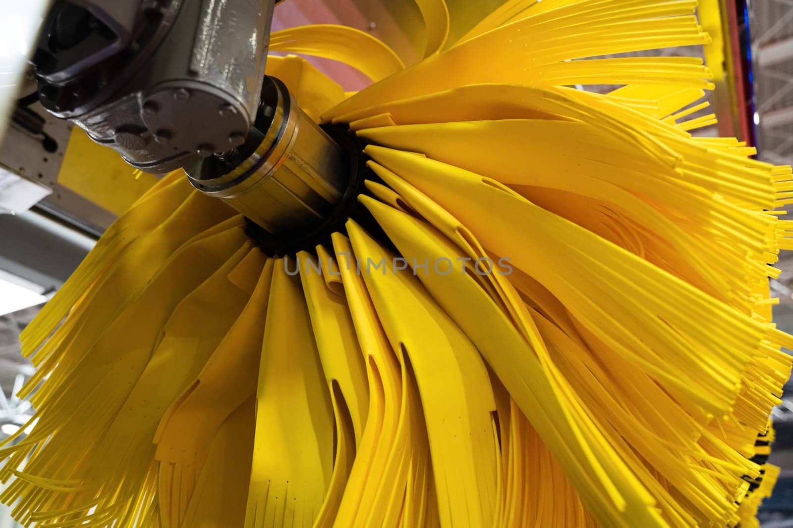 front view closeup detail of black and yellow automatic car wash system cleaning fiber sponge brushes on spinning rotor in an auto service garage station