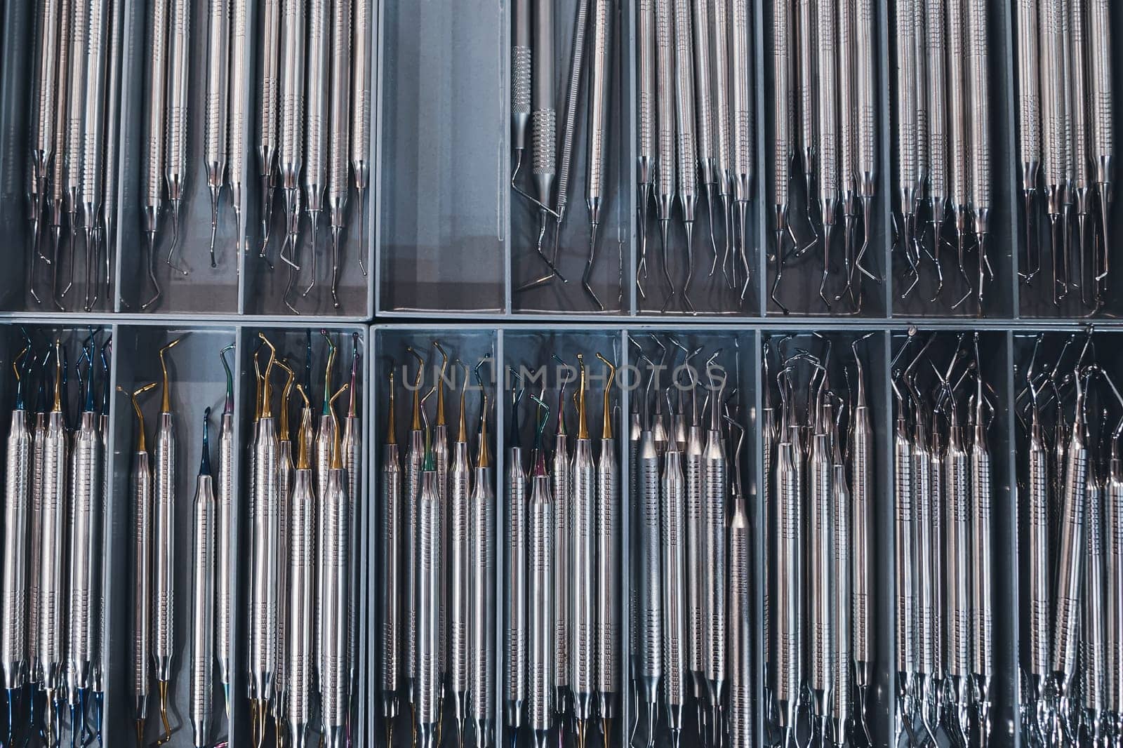top view closeup of row of many basic stainless steel dental tools supplies on display in medical boxes