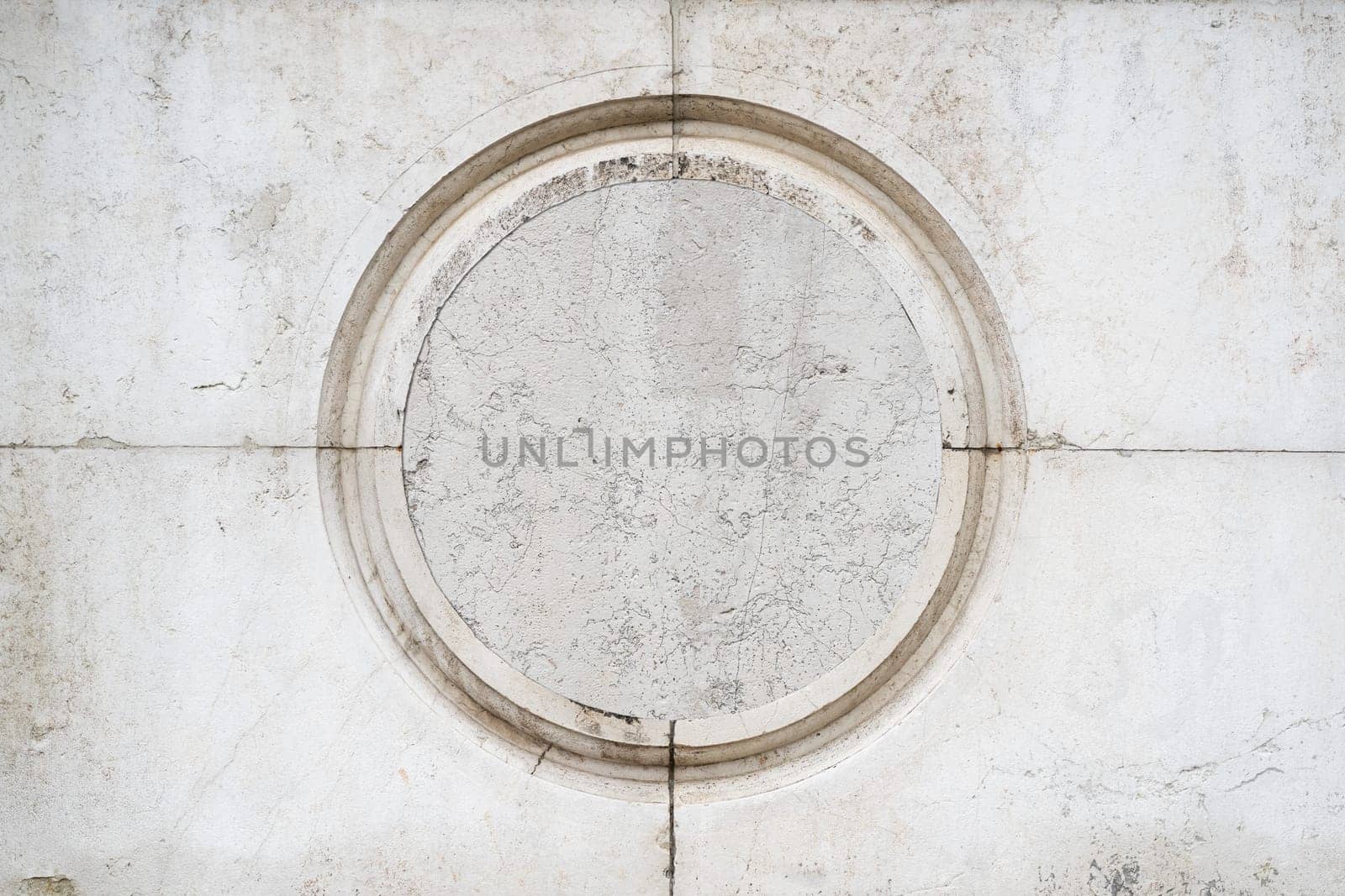 front view closeup of round empty classic ornamental frame signboard plaque on white marble stone wall
