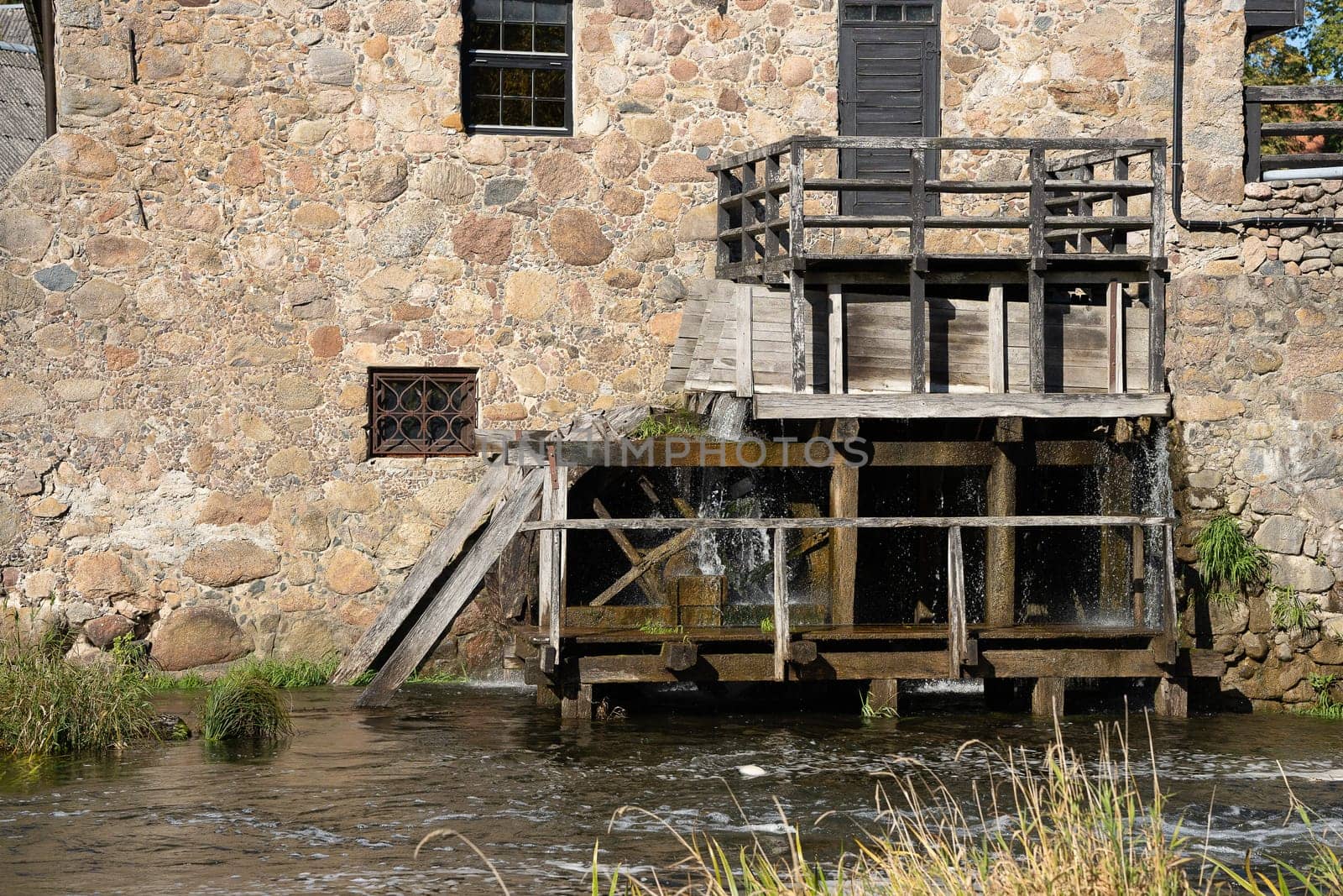 Water mill wheel rotates under a stream of water.